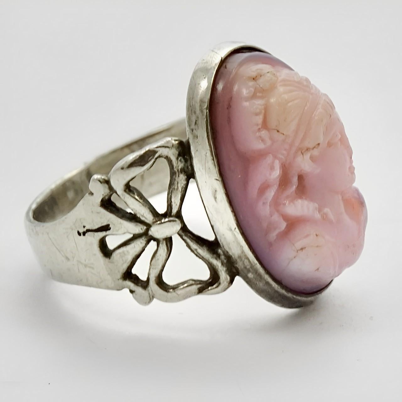 Lovely sterling silver and pink conch shell cameo ring, featuring bow design shoulders. Ring size UK I 1/2, US 4 1/2, and measuring diameter approximately 1.6 cm / .6 inch. There is scratching as expected, and the shell has some fine cracks.

This