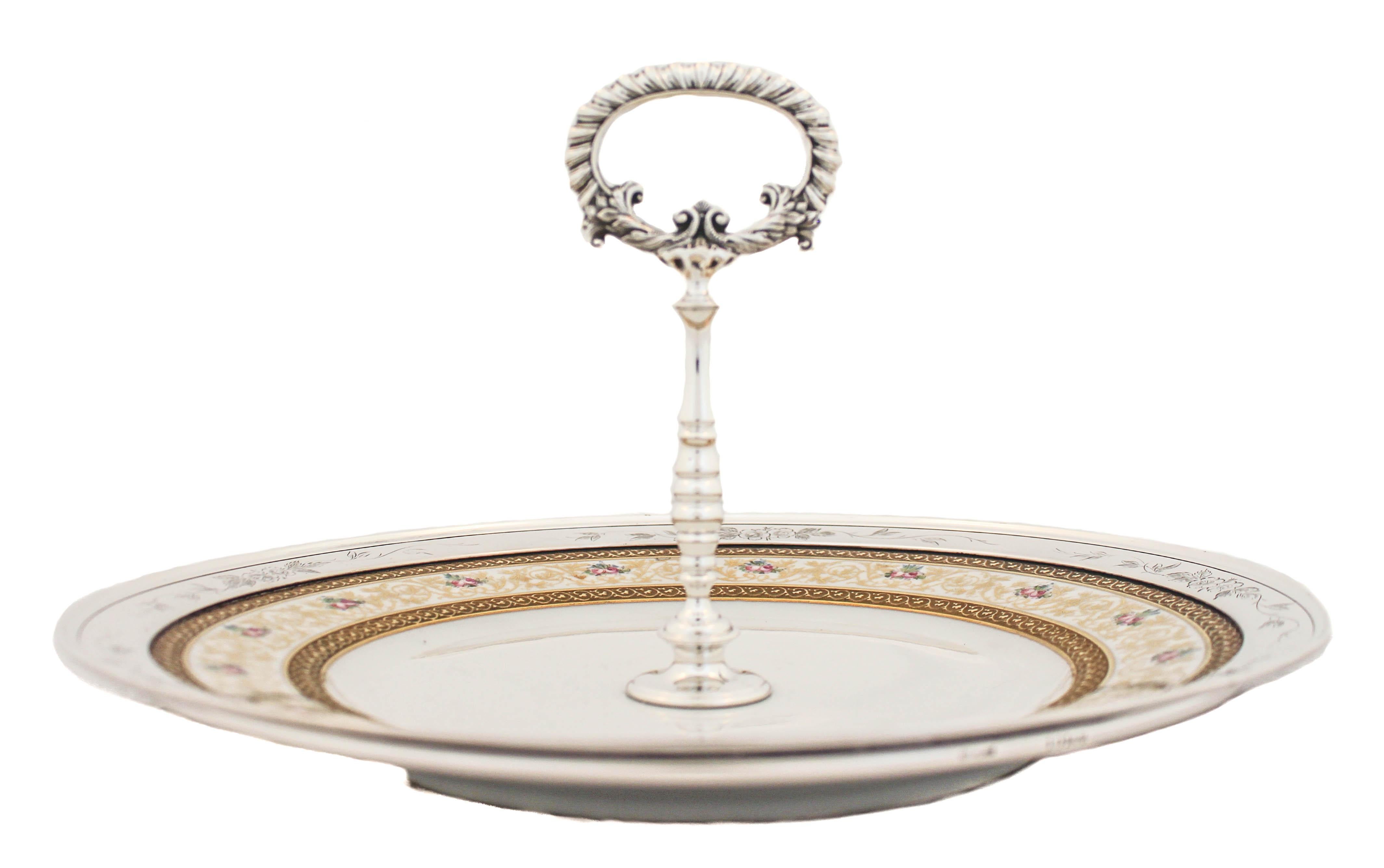 We are thrilled to offer you this sterling silver and porcelain dessert tray.  The edge and center handle are sterling silver while the inner tray is made of fine porcelain.  The silver rim has etched flowers and leaves and the handle has a gadroon