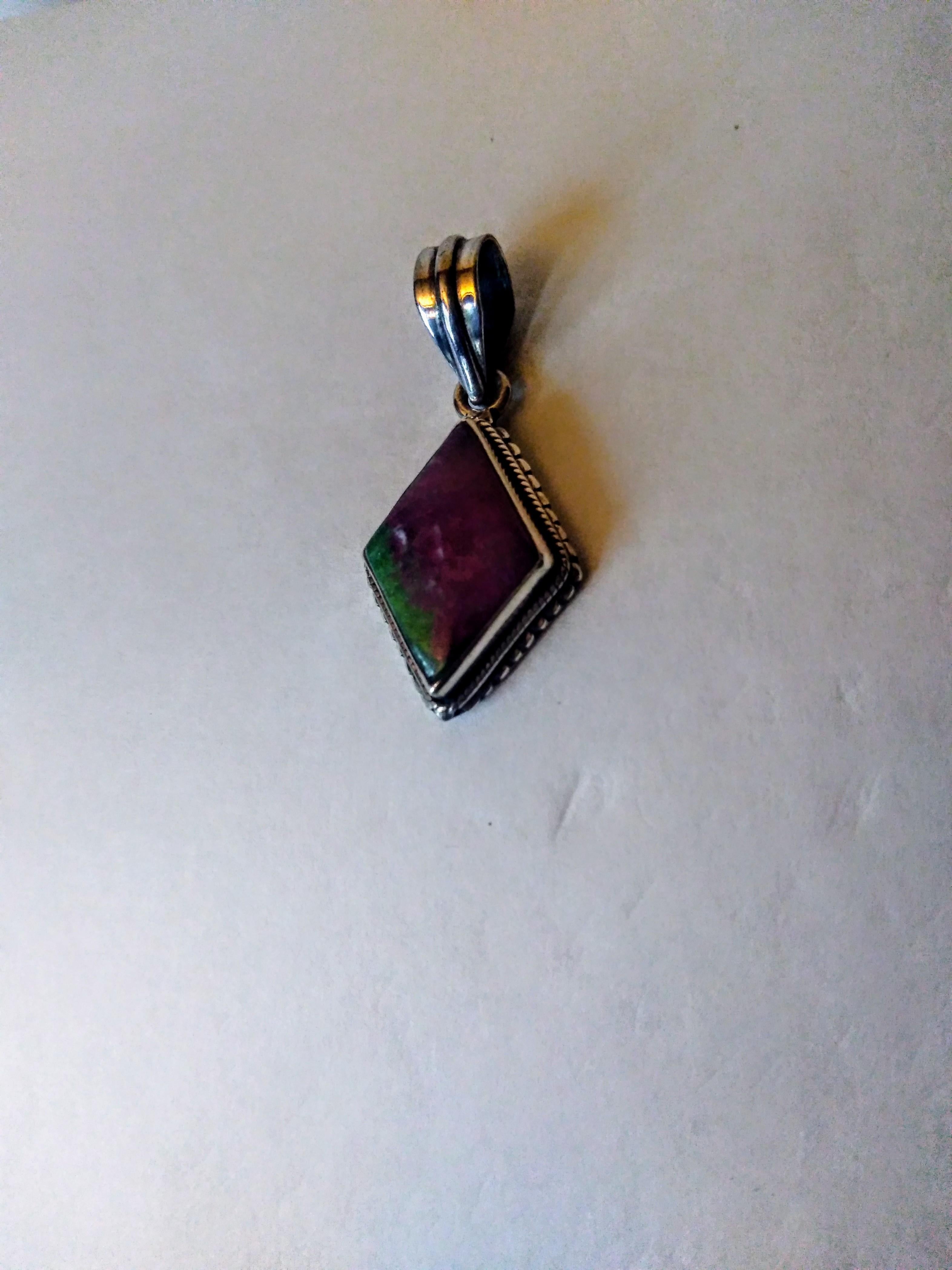 This is a beautiful pendant. It's made of sterling silver and has a beautiful piece of Zoisite as it's setting. The pendant has a beaded sterling edge. The Zoisite is purple with a green inclusion..

Free shipping.