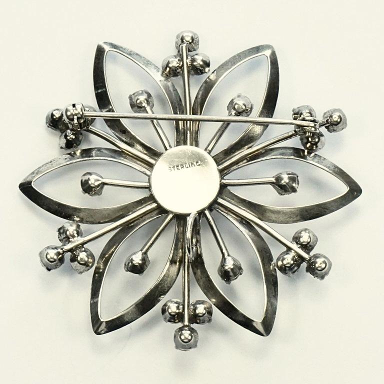 Magnifique broche fleur en argent sterling sertie de strass clairs. Il est muni d'une boucle de suspension. Diamètre de mesure 5,5 cm / 2,1 pouces. Il y a des rayures, comme on peut s'y attendre. La broche a été légèrement nettoyée.

Cette broche
