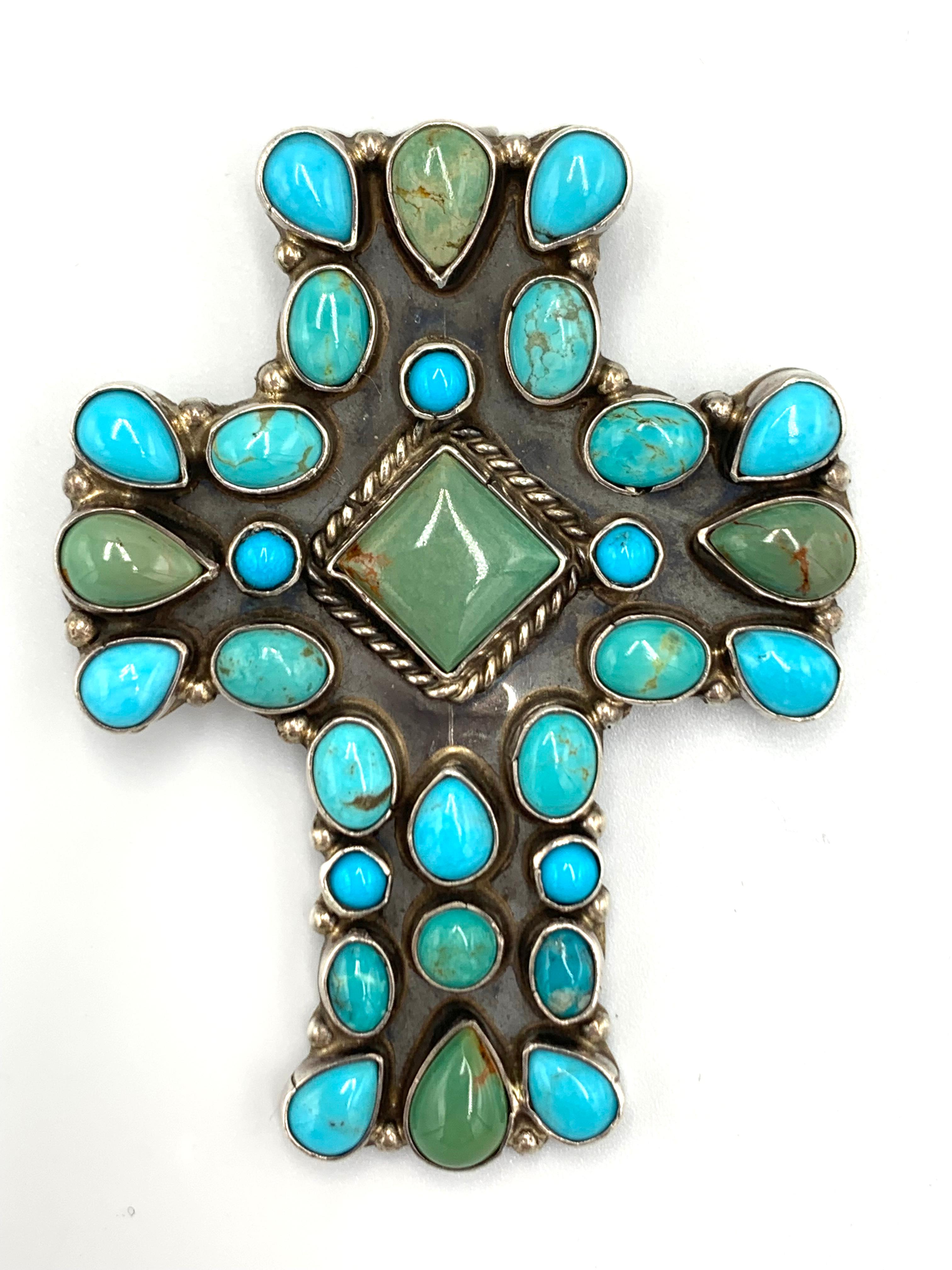 Questo sorprendente ciondolo a croce dell'argentiere Rocki Gorman di Santa Fe presenta 30 cabochon di turchese multicolore di varie dimensioni, tutti incastonati nell'argento sterling. Il ciondolo misura 2