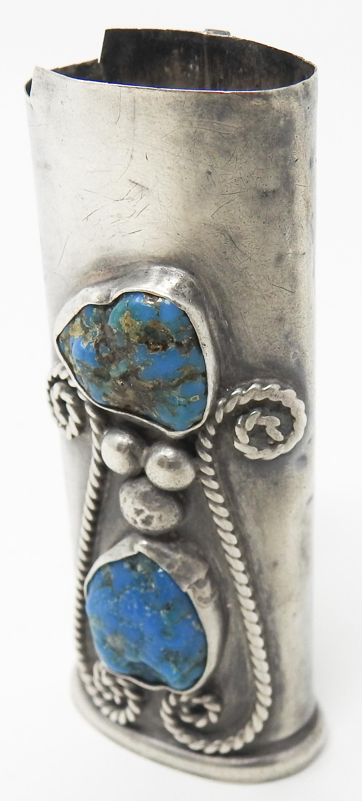Offering this handsome sterling silver and turquoise lighter case. The front has two big stones of turquoise that are set with 3 balls in between them and scrollwork, spiral filigree to either side. You can tell this piece is hand crafted and the