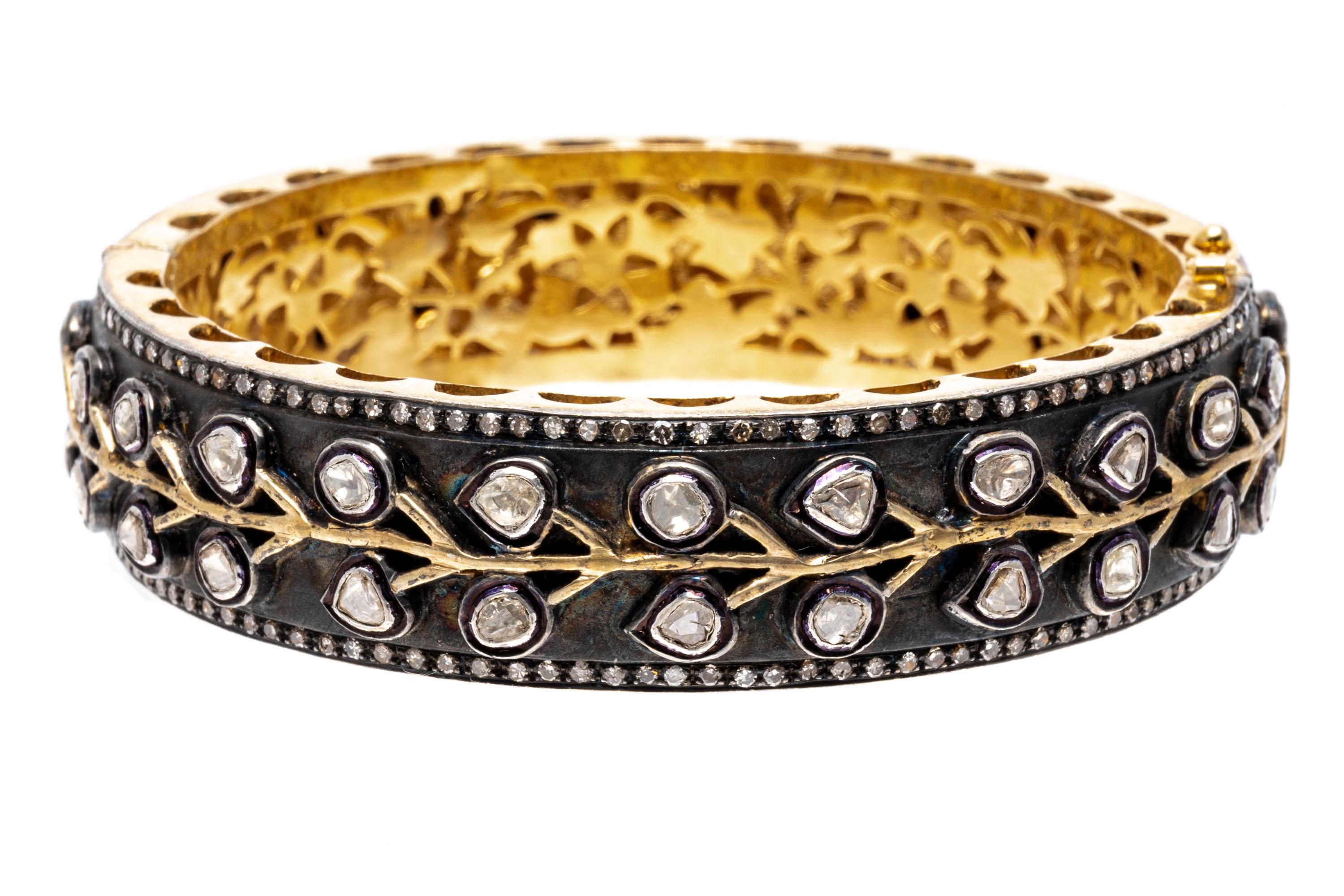 Sterling silver vermeil bracelet. This spectacular bracelet is a wide, hinged bangle bracelet, decorated with a white top and vermeil sides and interior, and set with a center vine pattern, adorned with bezel set, macle cut diamonds of varying