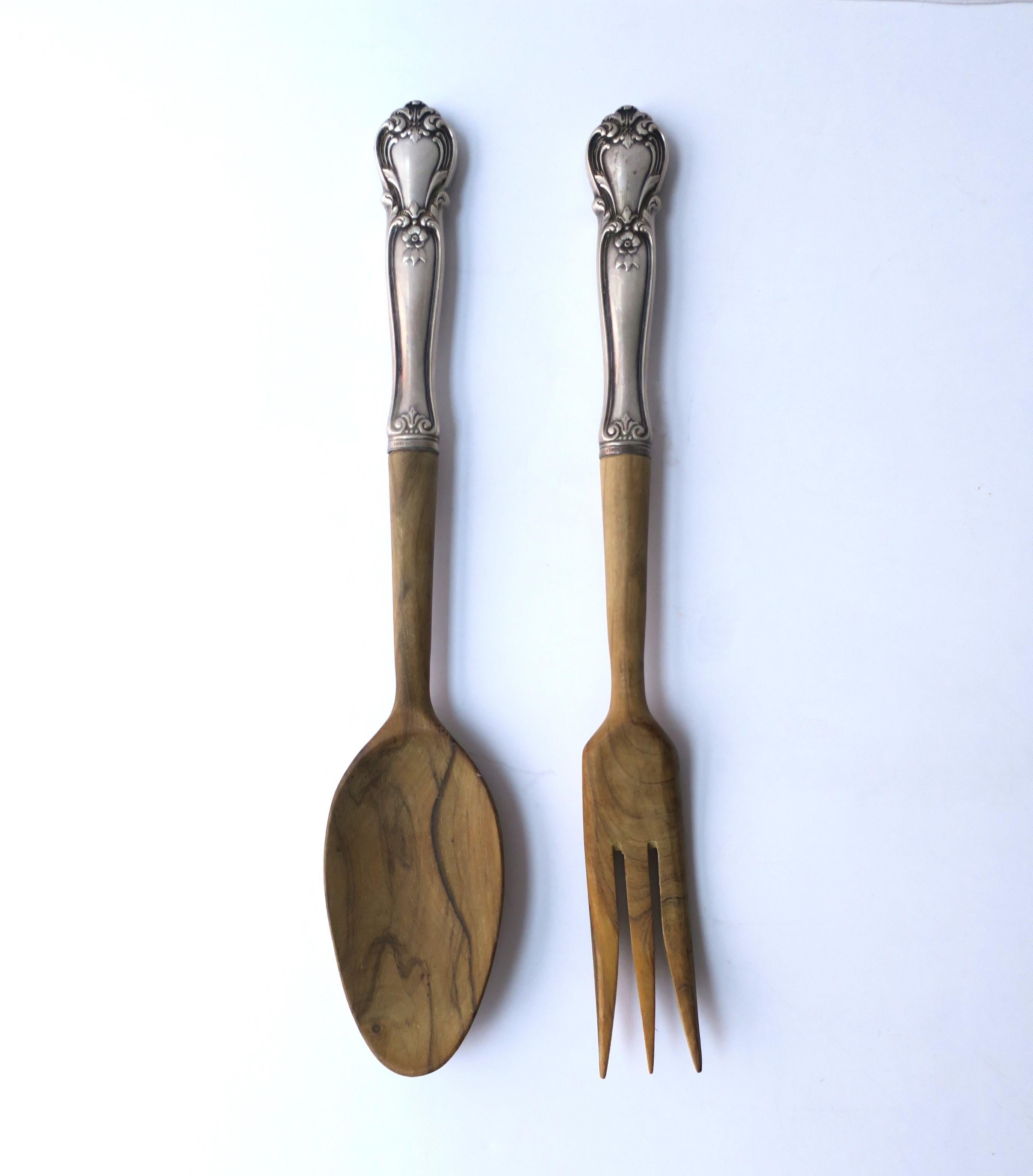 A spoon and fork sterling silver and wood salad serving utensil set. Set is wood with sterling silver handles. Handles are marked on front and back 'Sterling'. Dimensions: 10.25