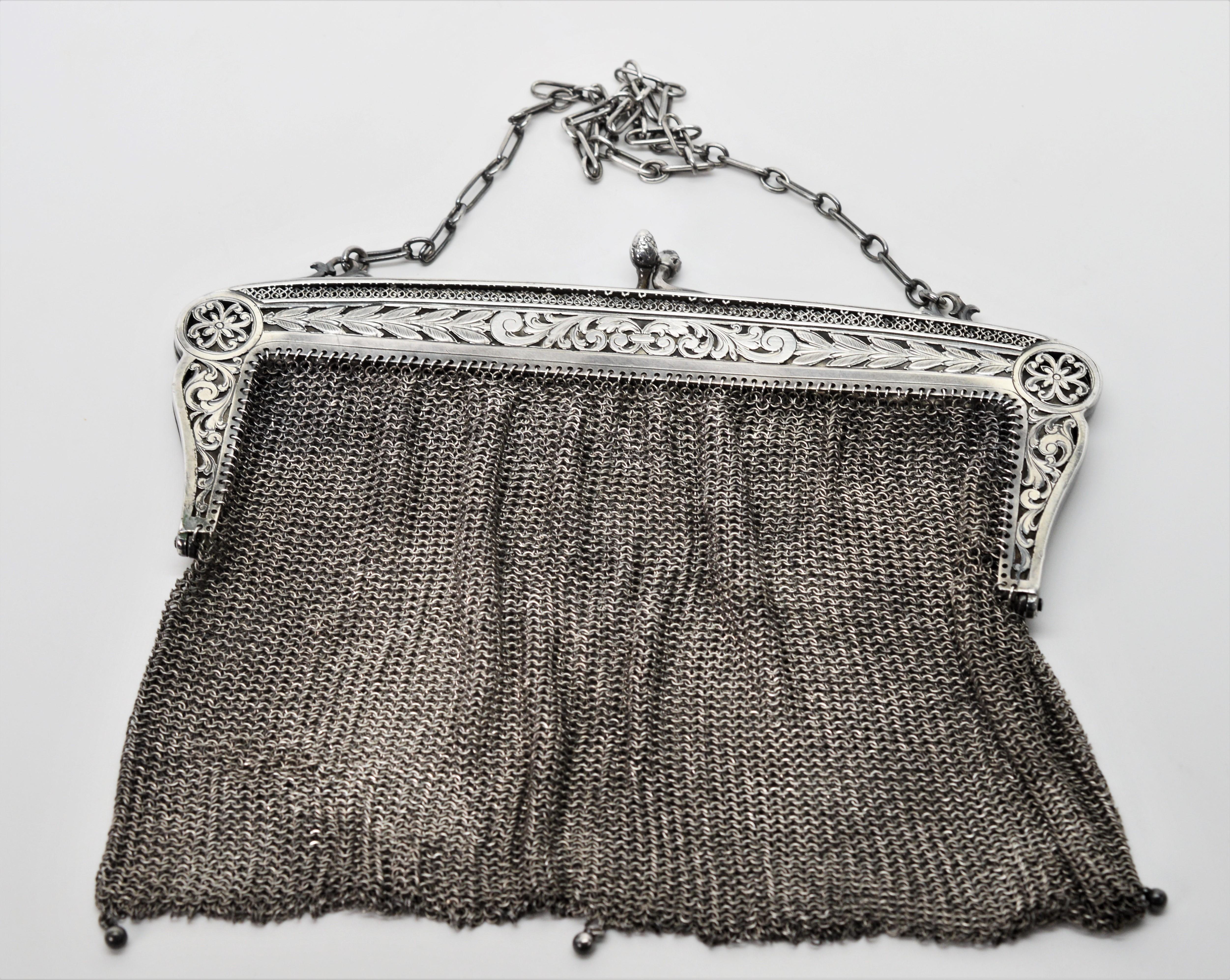 Exquisite filigree and engraving is on the sterling silver frame of this pre - 1888 German chain mail mesh antique purse evening bag.
The purse frame has a working kisslock snap with an acorn design ball closure. The frame's reverse side has an