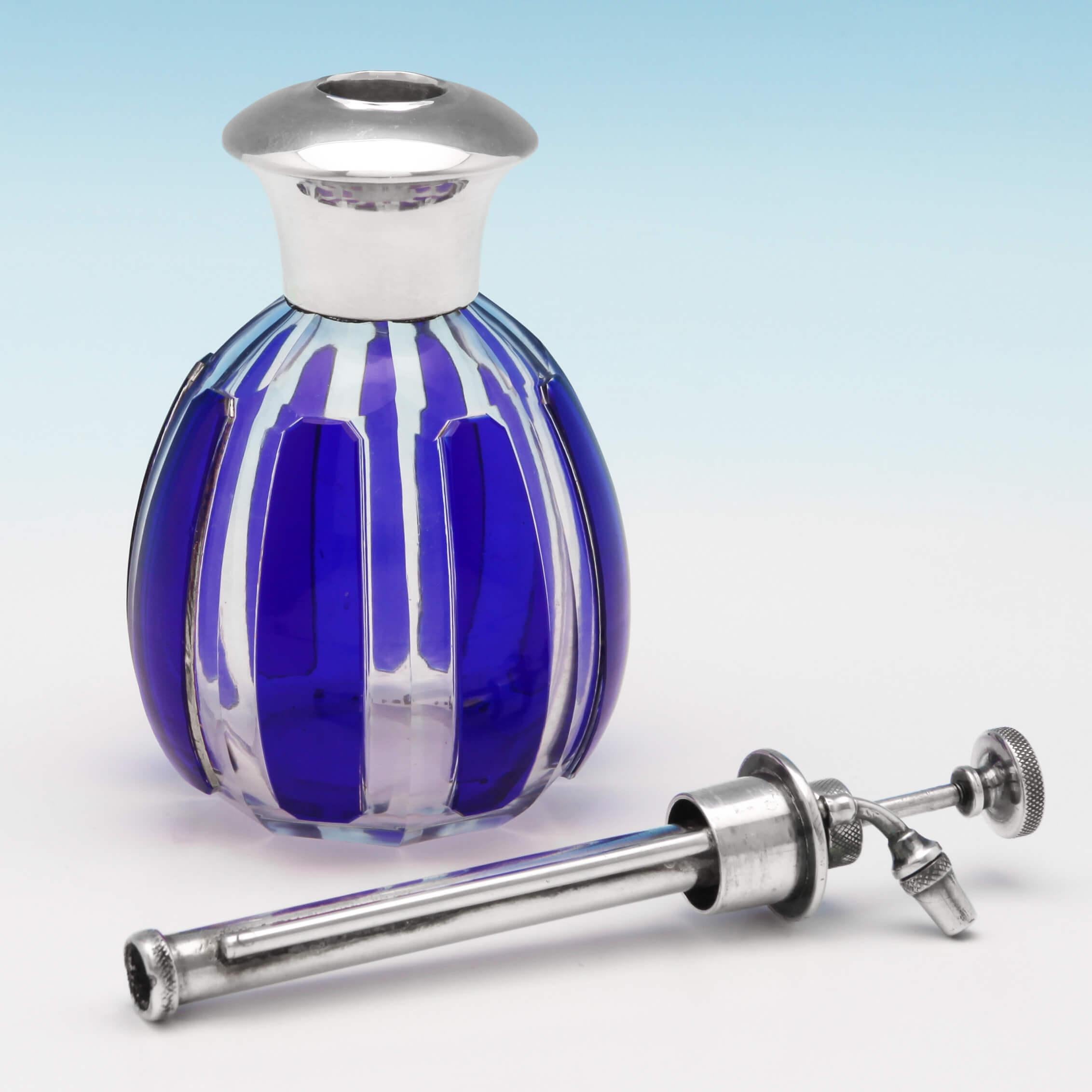 Hallmarked in Birmingham in 1925 by Charles S. Green & Co., this rare, George V, sterling silver atomiser, is in the Art Deco style, and has a clear glass body with overlaid blue panels. The atomiser measures 6