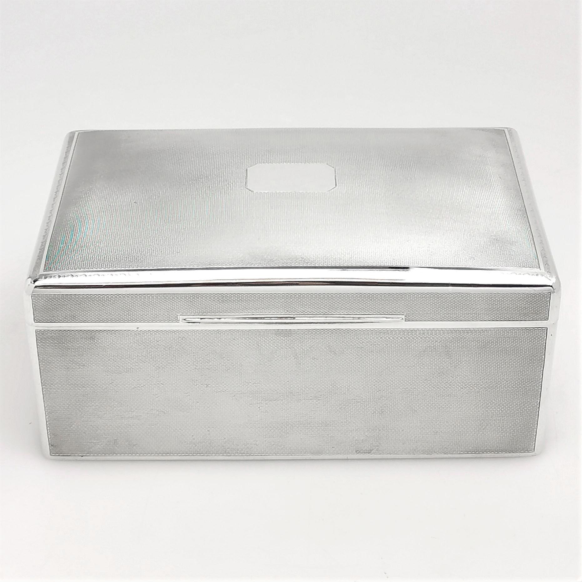 An antique solid silver cigar box / cigarette box with a classic engine turned pattern exterior. The box has a lightly fitted hinged lid with a blank cartouche in the centre to allow for engraving if desired. The interior of the base of the Box is