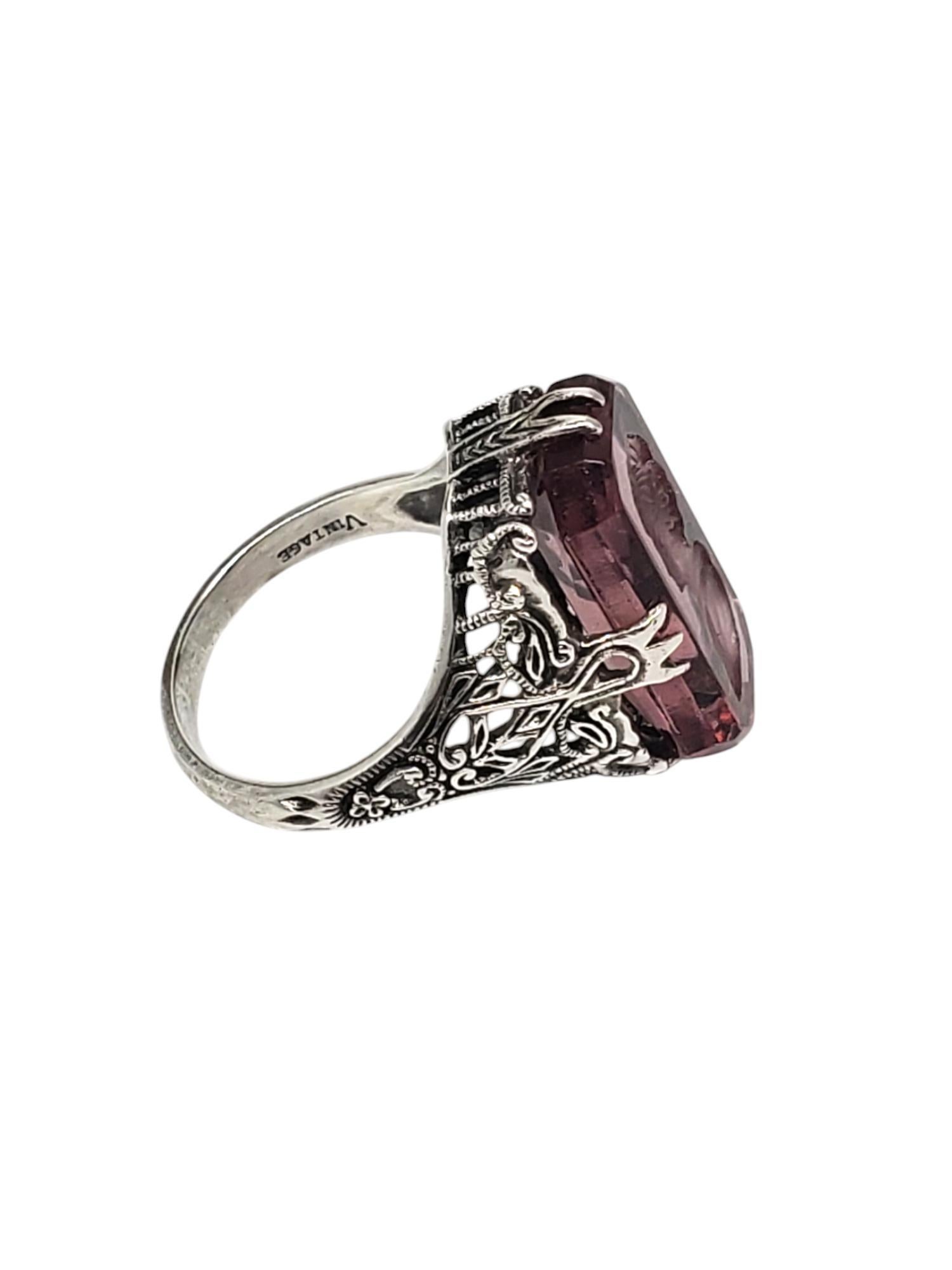 Sterling Silver Filigree Intaglio Purple Stone Ring 

This vintage ring features a large purple stone set in a filigree sterling silver setting by Heirloom 73 Sterling. Intaglio design of cameo. 

Shank: 2.3 mm

Size: 10

Front of ring: 19mm x