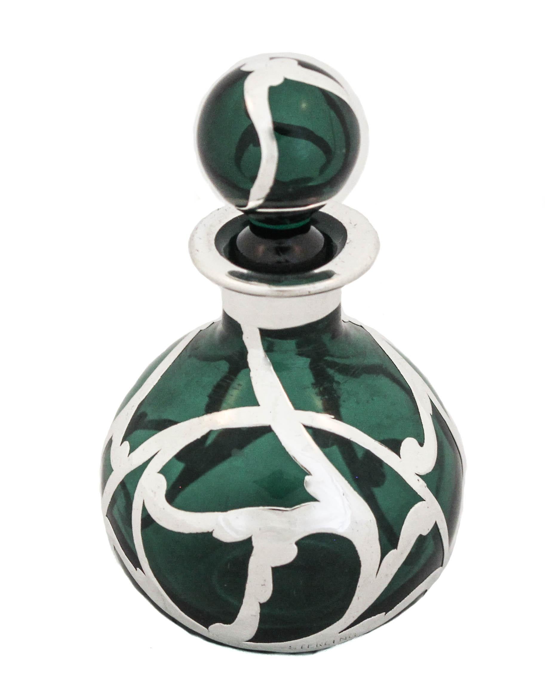 Nous vous proposons un flacon de parfum en argent et cristal de la période Art Nouveau.  Le verre est d'un vert profond et est recouvert d'une couche d'argent.  Le motif en argent est la quintessence de l'Art nouveau avec ses tourbillons organiques