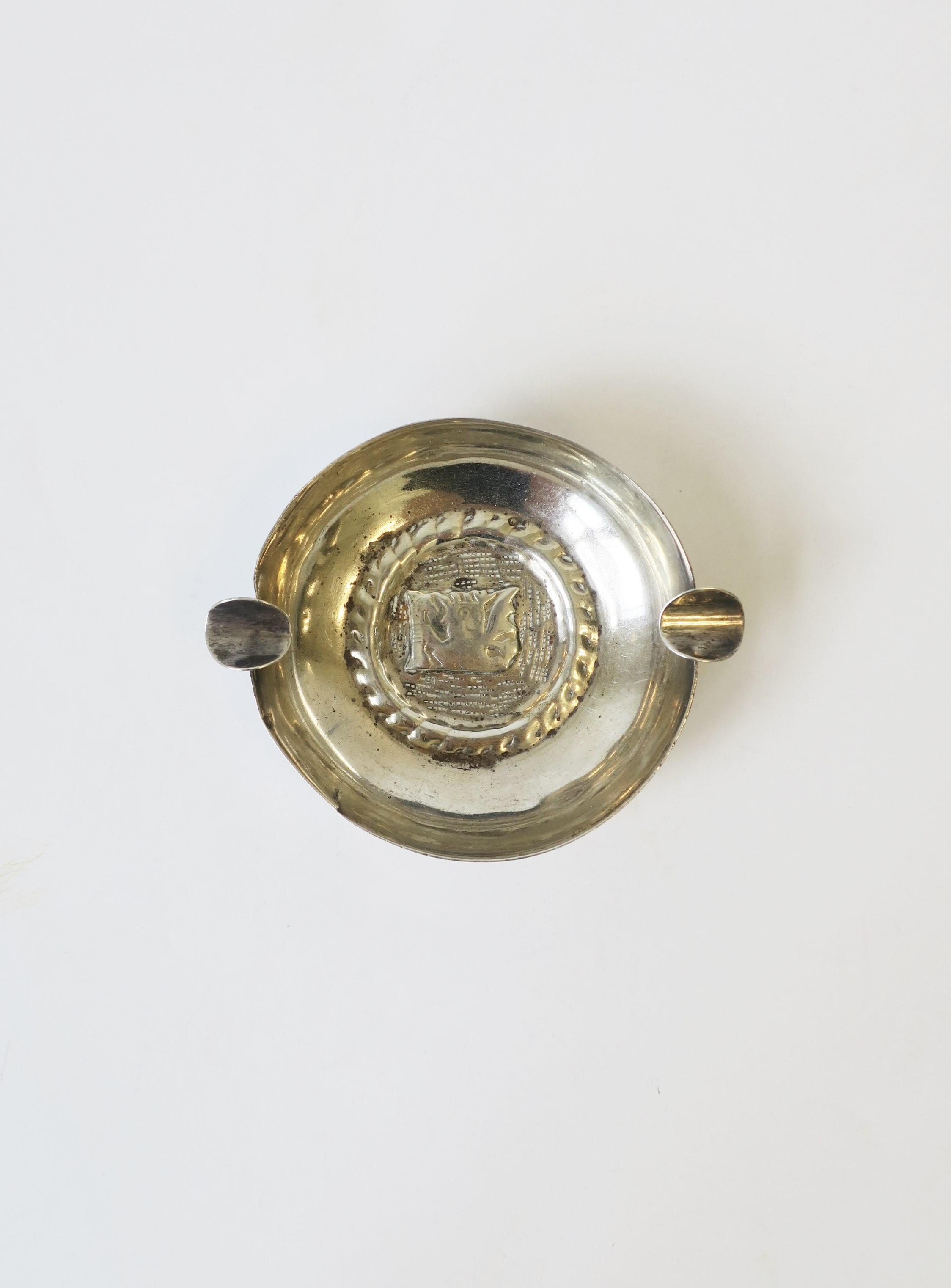 A small hand-crafted sterling silver ashtray with repousse design, circa 20th century, Peru, Latin America. Ashtray can hold two cigarettes as shown with its two-sterling silver supports. Alternatively, piece can be used as a small catchall; shown