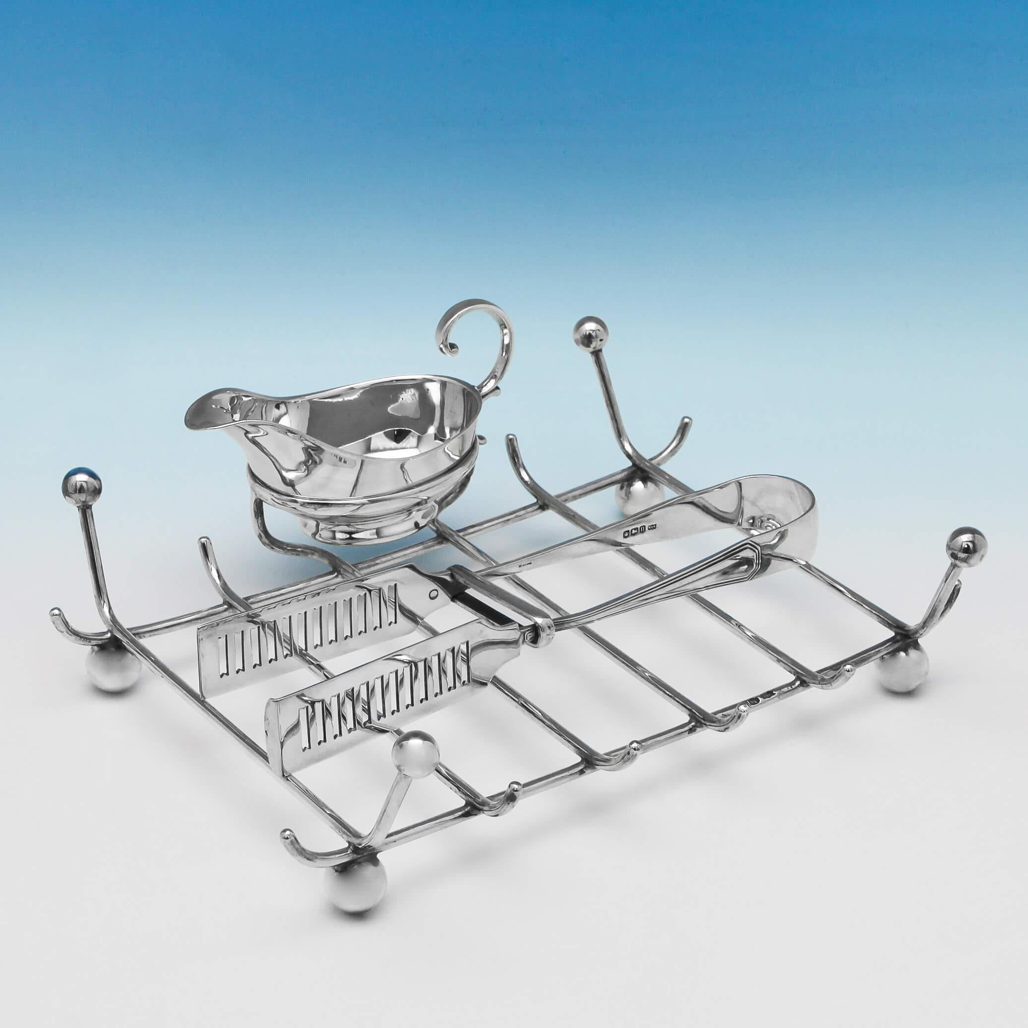 Hallmarked in Sheffield in 1930-1931 by Mappin & Webb, this handsome, George V, sterling silver asparagus dish, features serving tongs, a butter boat and a draining rack, all fitted on a shaped border tray, which stands on ball feet. The asparagus