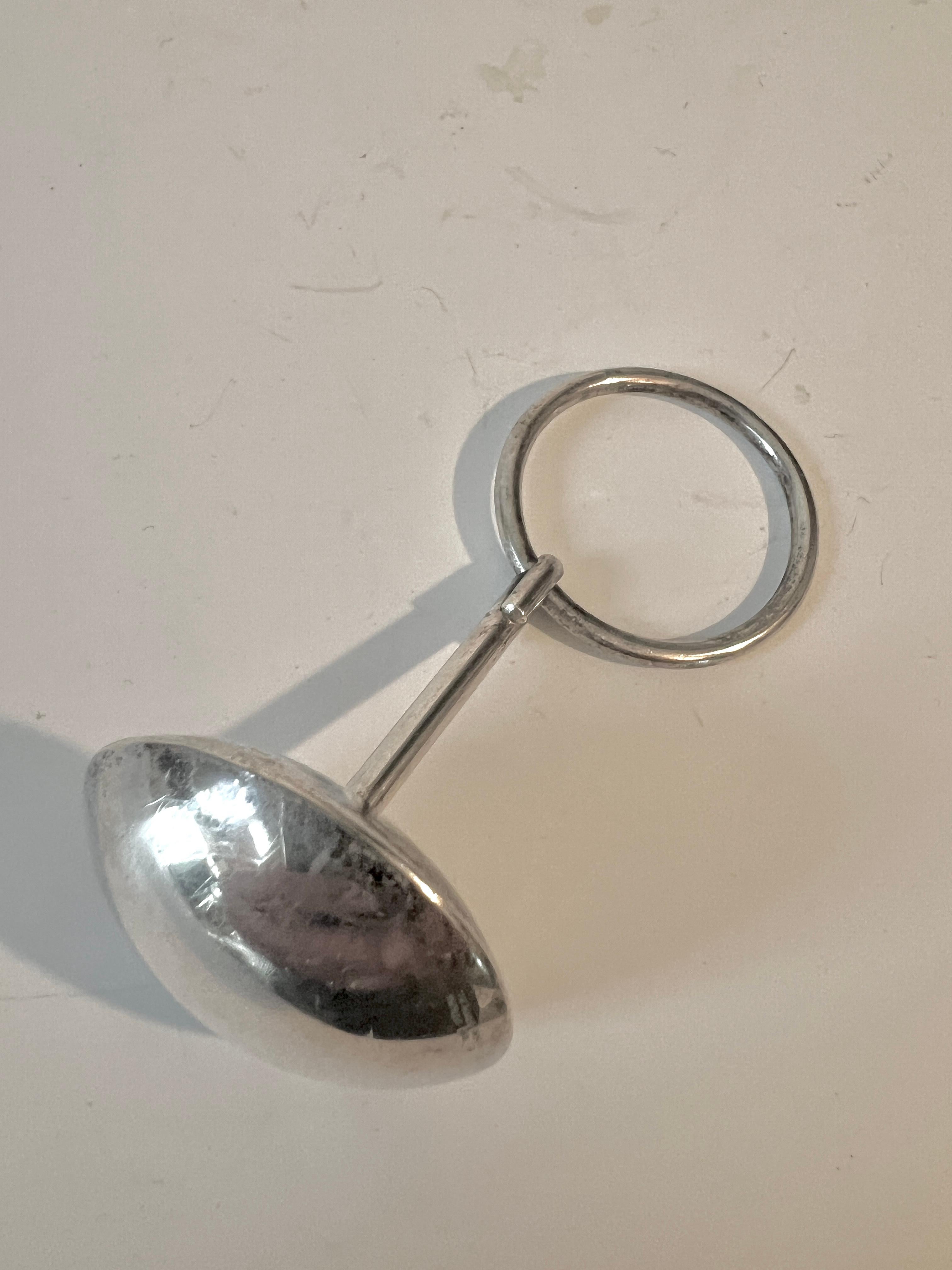 Un unico e prezioso sonaglio per bambini in argento sterling.  Questo pezzo è dotato di un anello che può essere tenuto in mano e permettere al pezzo di rotolare oppure può essere tenuto sul gambo e fatto tintinnare.

Fotografare questi piccoli