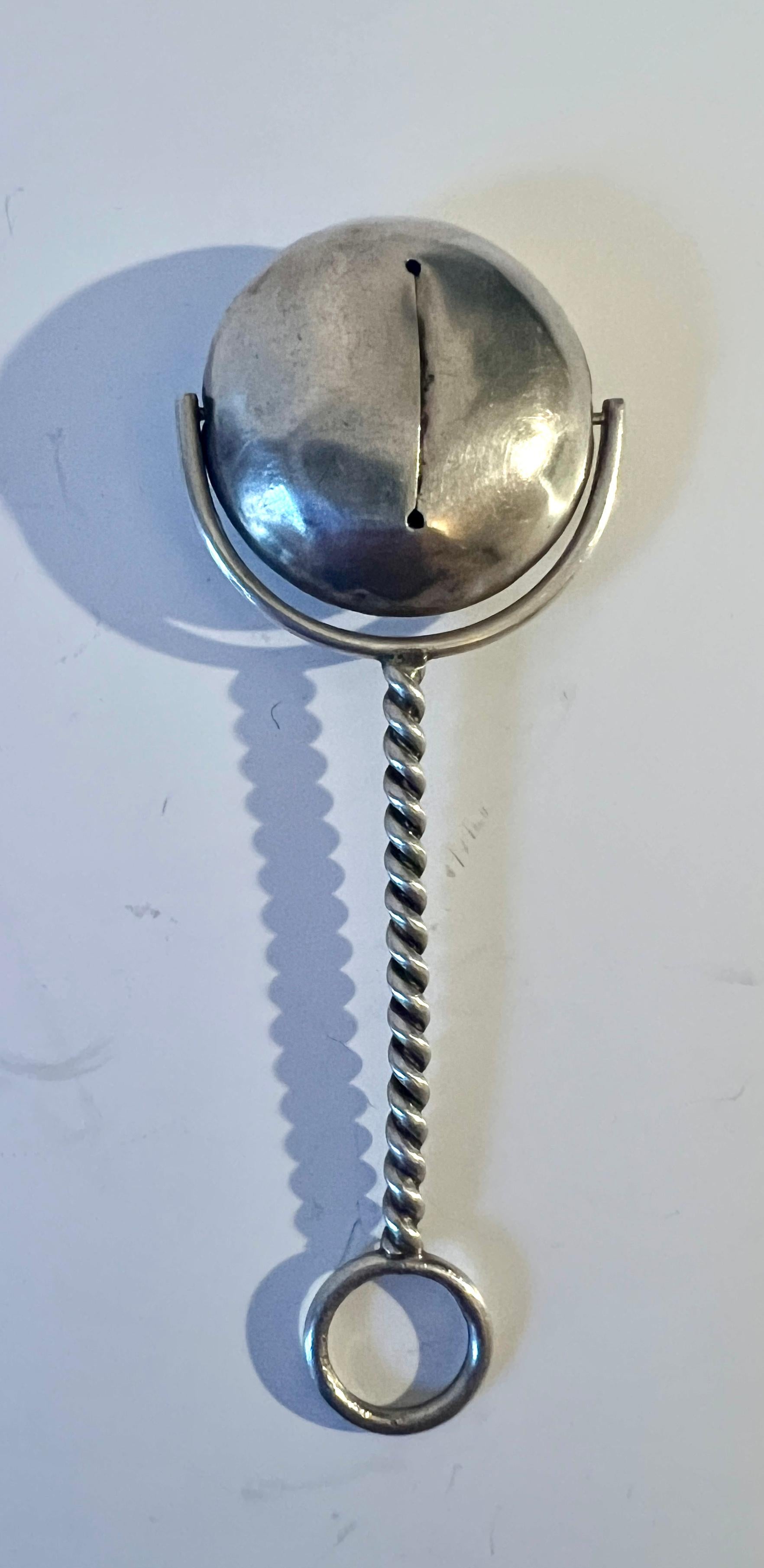 Un semplice e grazioso Baby Rattler in argento sterling.  Il manico è in argento Serling ritorto e la testa del serpente fa un leggero rumore e gira tra le braccia che la tengono.

Un meraviglioso sonaglio pratico o un pezzo decorativo.

Abbiamo
