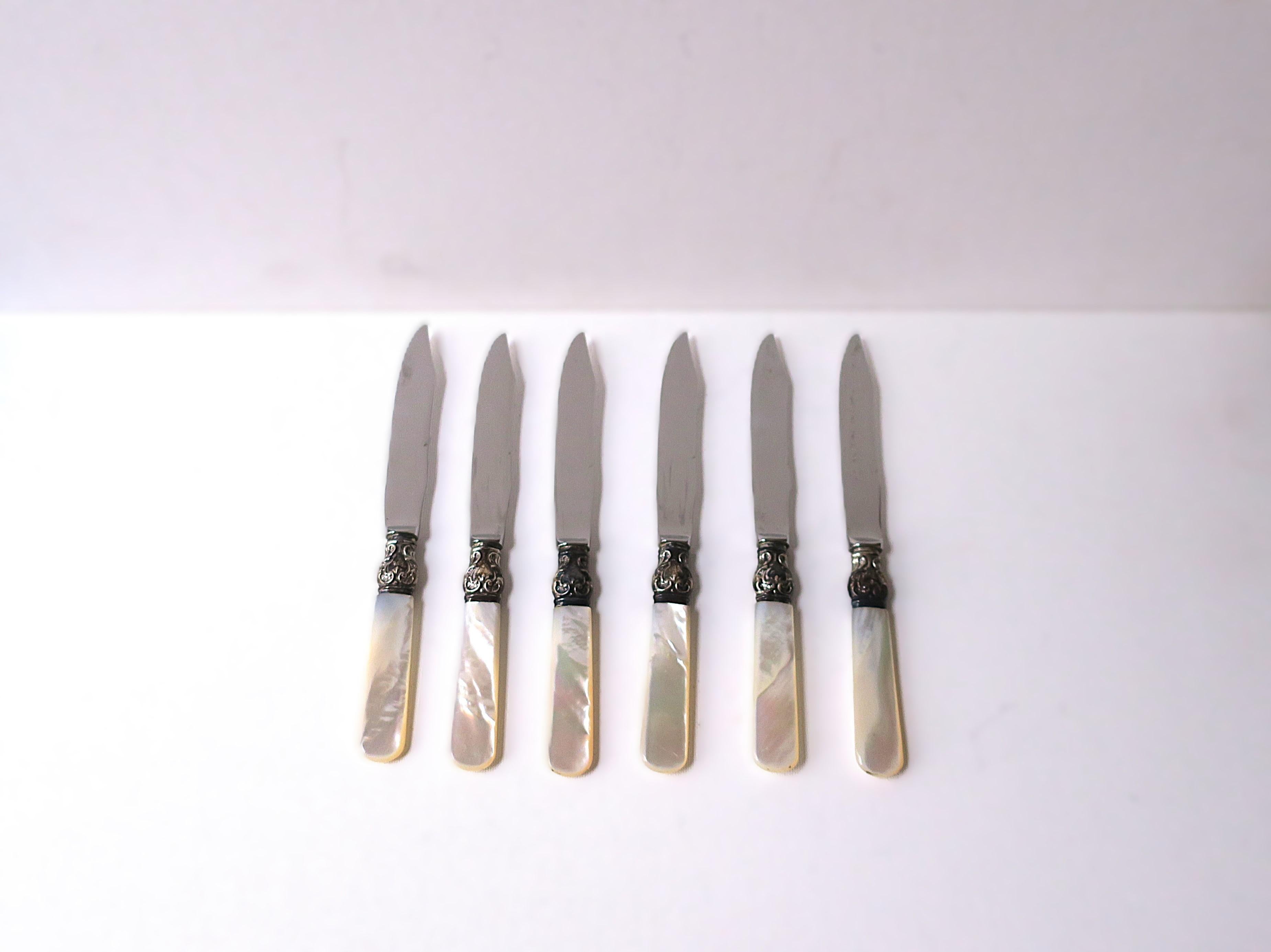 Precioso juego de seis (6) cuchillos de bar para fruta o aperitivo, de plata de ley y nácar, de finales del siglo XX. Las empuñaduras son de nácar y están unidas a las hojas de acero inoxidable por una virola/collar de plata de ley. Marcado