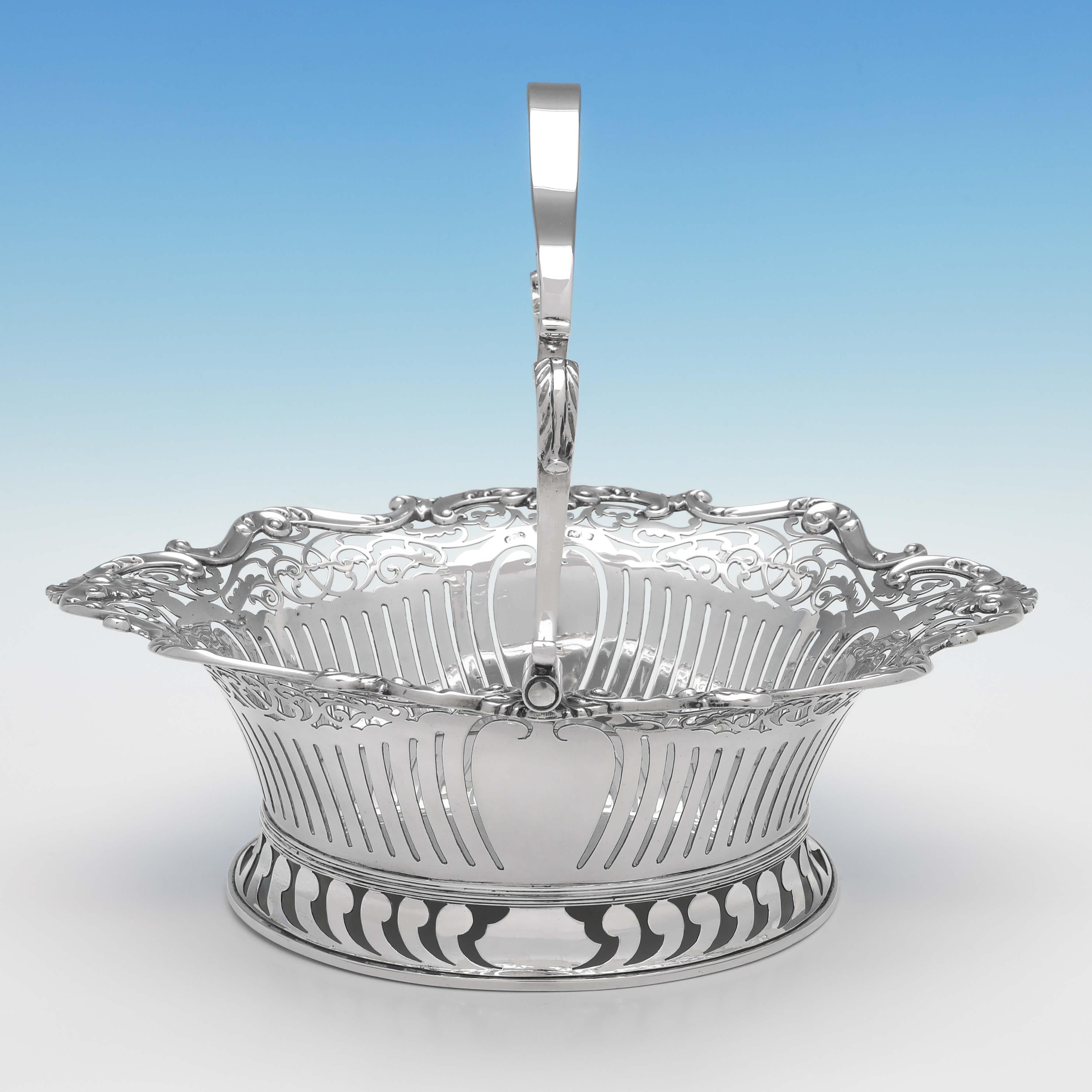 Hallmarked in Birmingham in 1903 by Elkington & Co., this delightful, antique sterling silver basket, features pierced decoration to the body and foot, an applied shell and scroll border, and an acanthus detailed swing handle. The basket measures