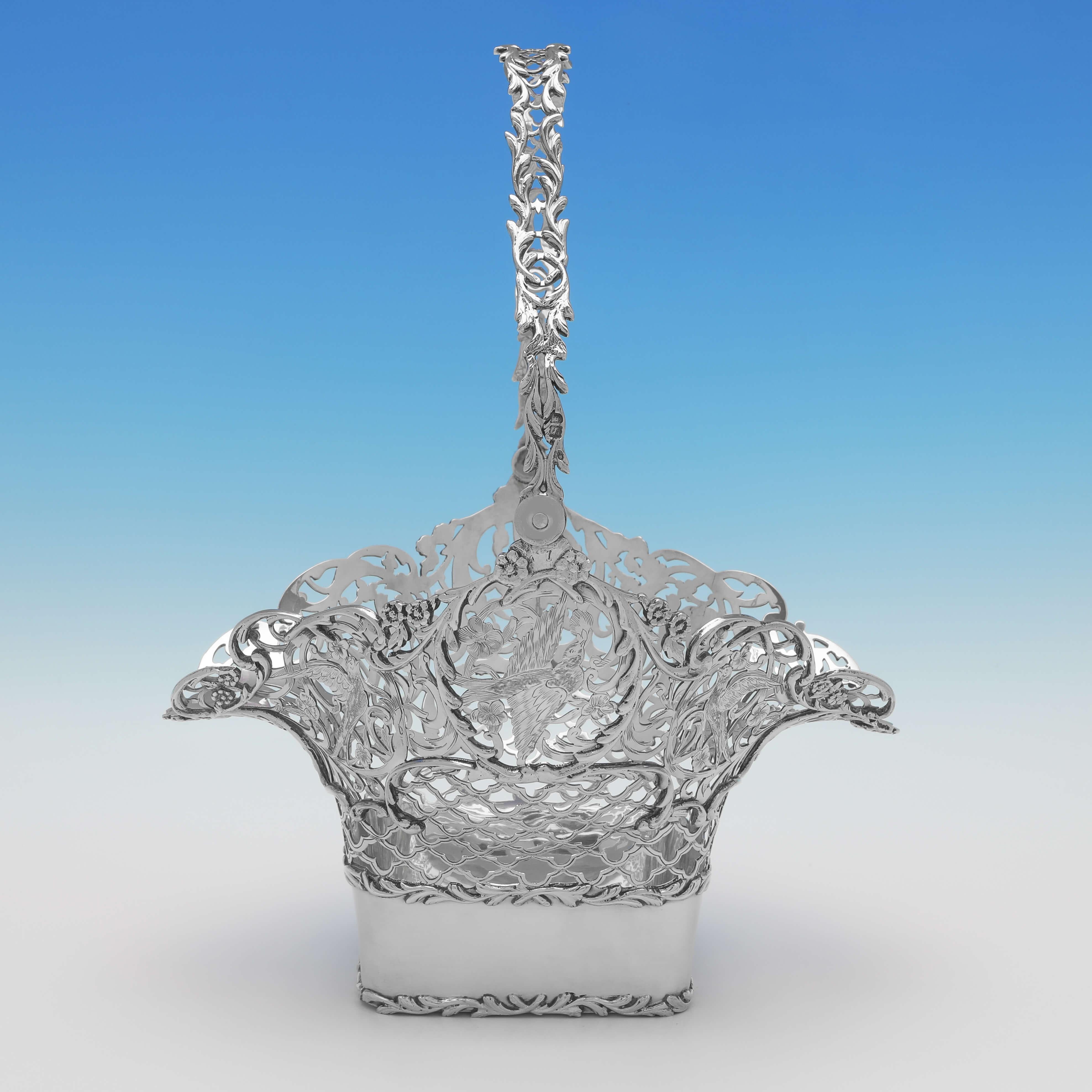 Hallmarked in London in 1907 by Elkington & Co., this striking, antique sterling silver basket, features pierced and engraved sides depicting birds and floral motifs, and a cast acanthus border and pierced handle. The basket measures 7.75