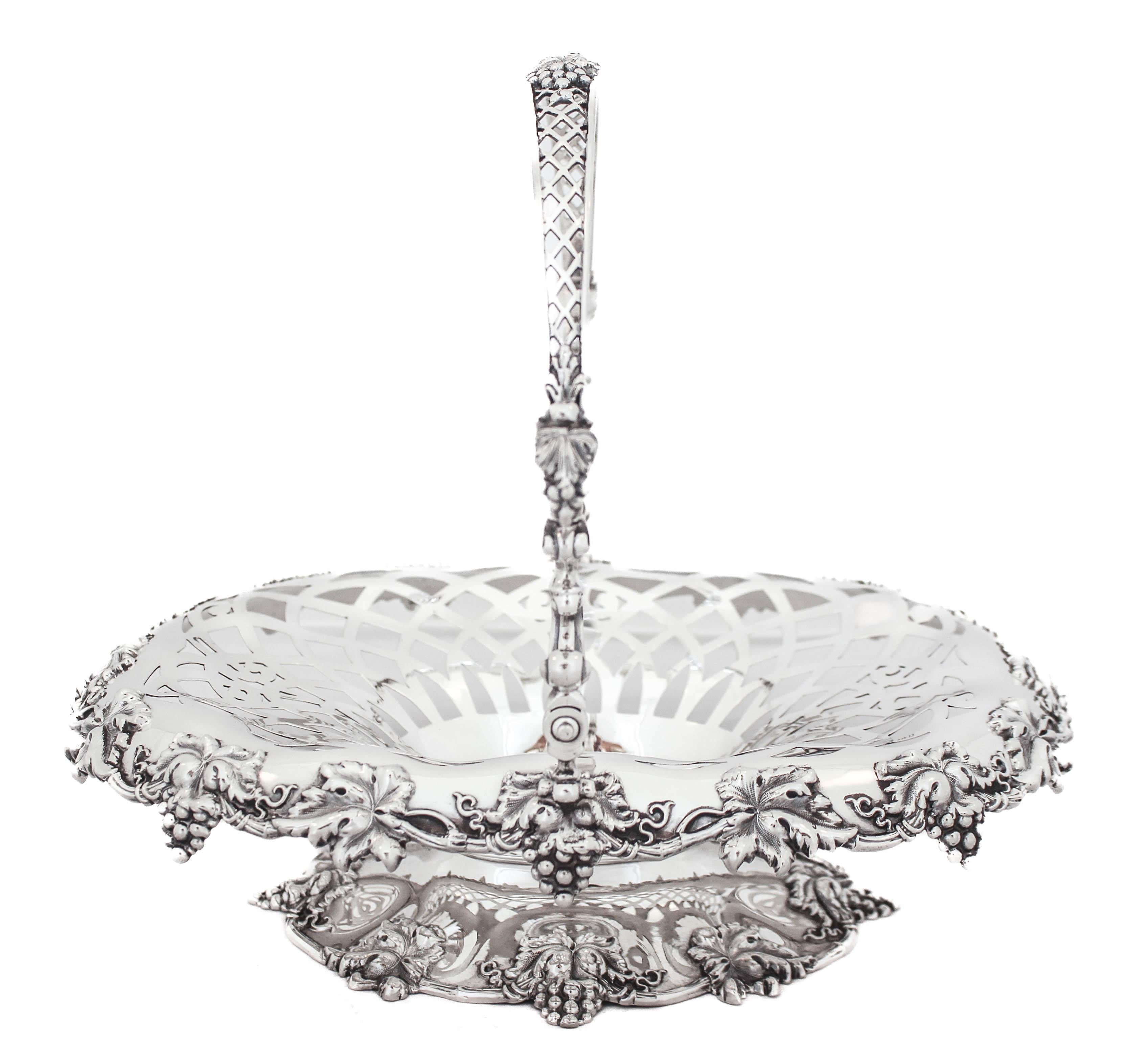 Being offered is a sterling silver basket by William Durgin Silver.  It has clusters of grapes and leaves hanging off the rim and along the base.  The sides of the basket are reticulated in a geometric arrangement.  The handle has both designs;