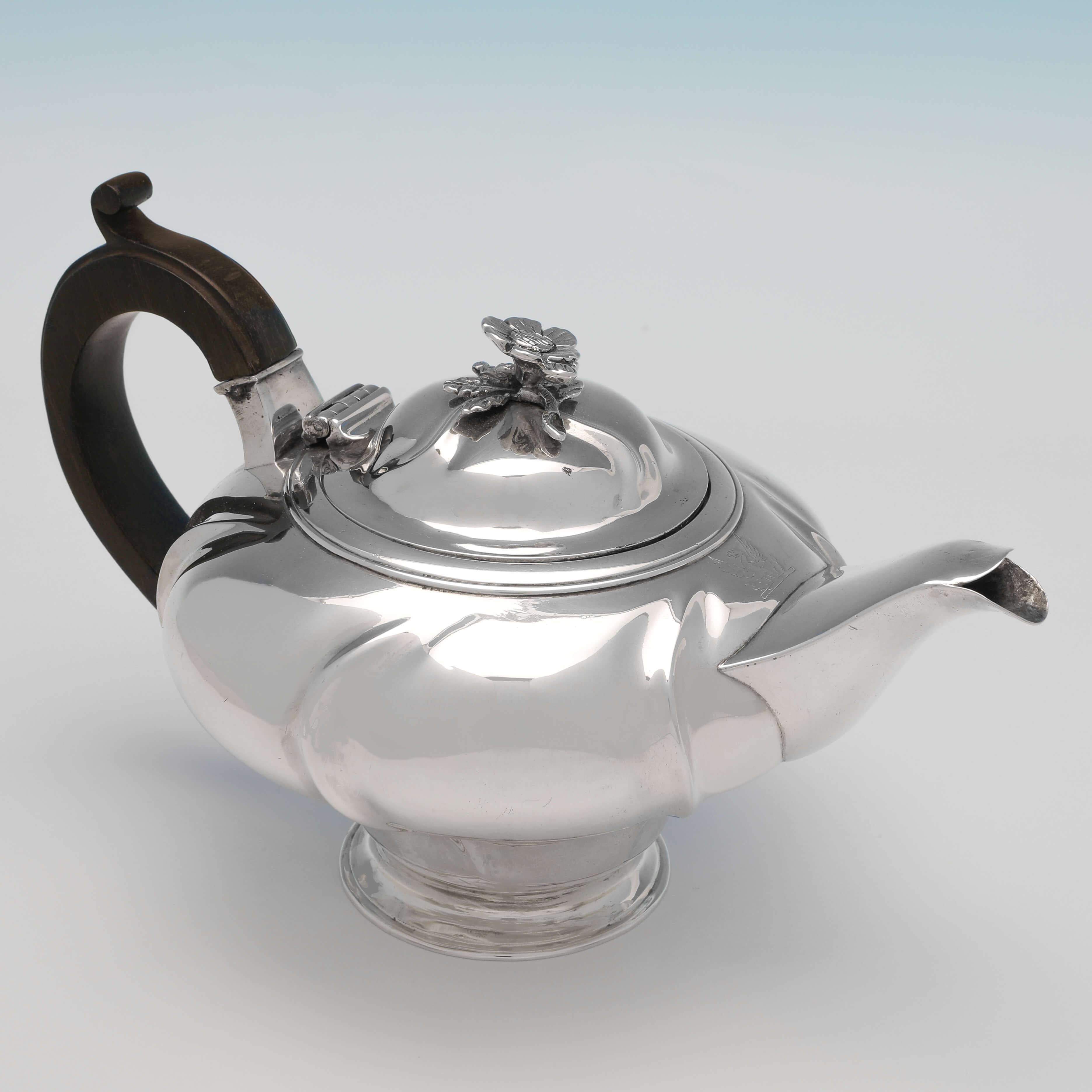 Hallmarked in London in 1824 by John Wakefield, this delightful, George IV, antique sterling silver Batchelor Teapot, is round in shape, and has an engraved crest and a wooden handle. The teapot measures 5