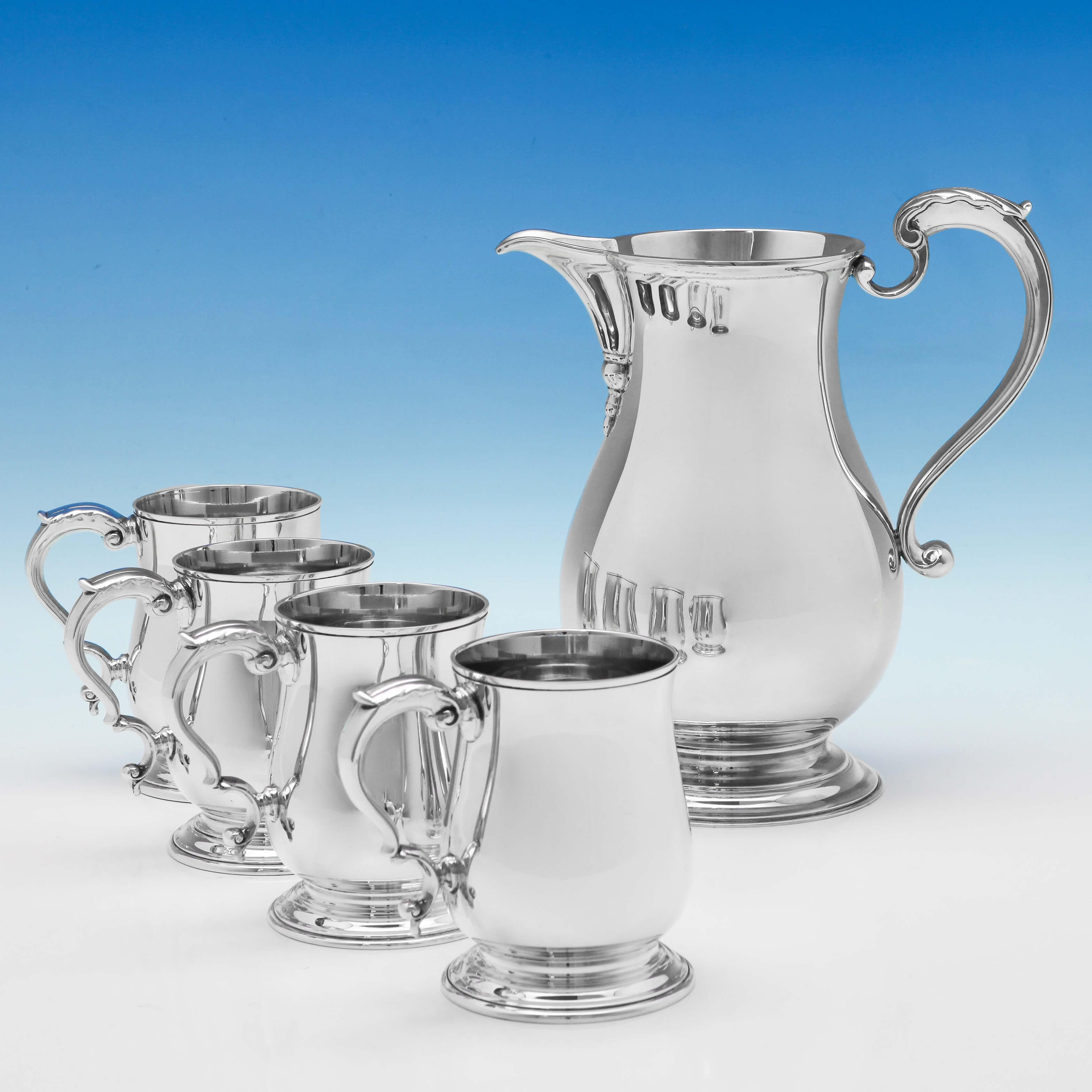 Hallmarked in London in 1962 by C. J. Vander, this handsome, Sterling Silver Beer Jug and set of Four Mugs are plain in style featuring reed borders and acanthus top scroll handles. The water jug measures 8.25 inches (21cm) tall, by 7.5 inches