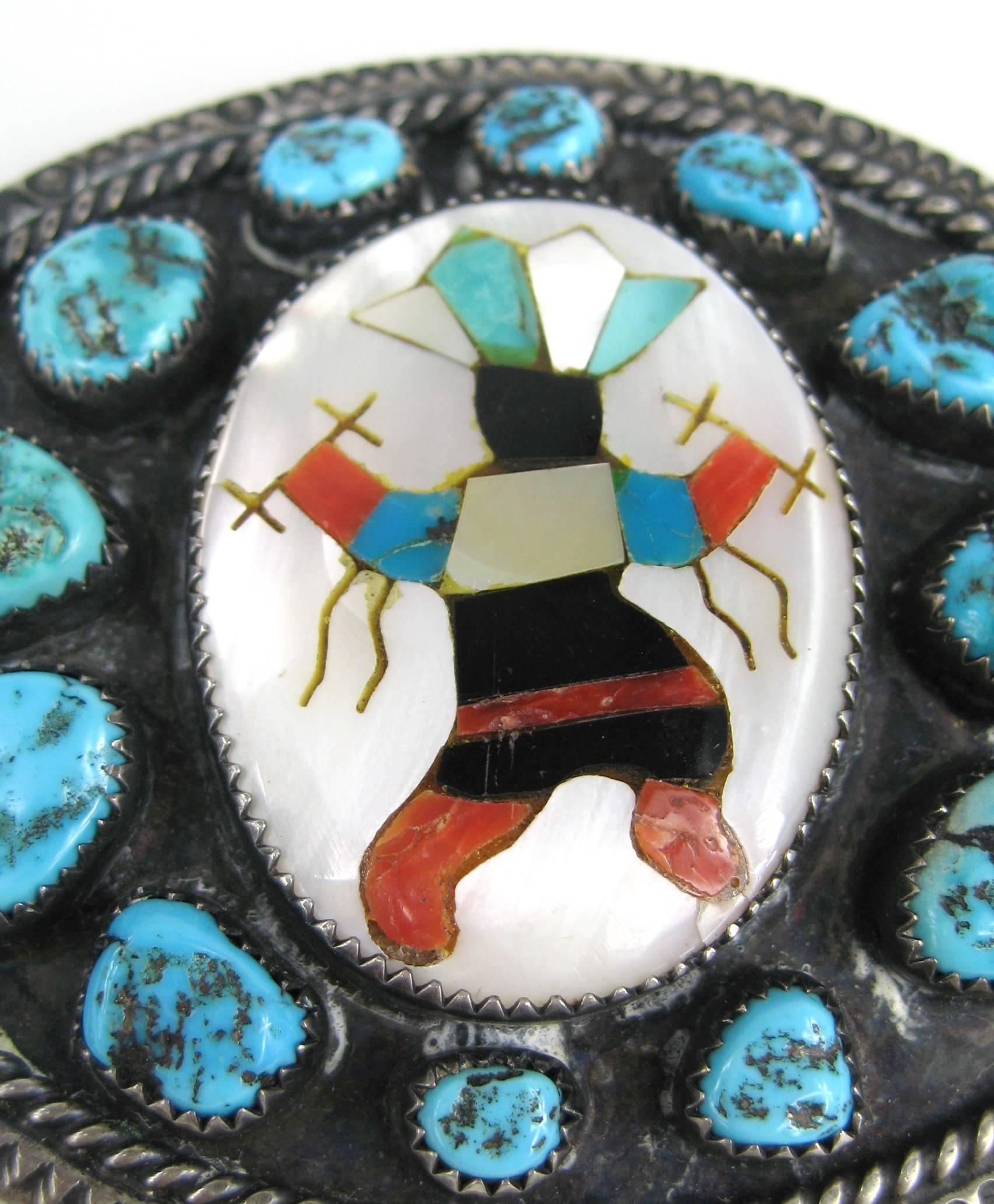 Large Hand set Turquoise stones surrounding a intricate Zuni Warrior set in sterling silver. Measures 3.00 inches w x 2.50in. Hallmarked LBJ on the back side of the buckle. Coral, Turquoise, mother of pearl inlay. This is out of a massive collection