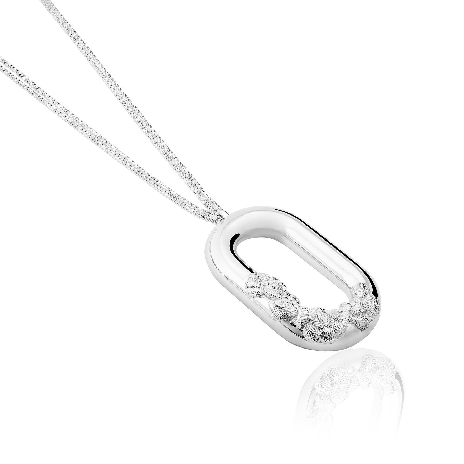 The Bordados Link Pendant from the Bordados Collection by TANE is made in sterling silver. A pendant hangs from a chain of 31.4¨, the symbol of TANE's jewelry trade that supports a floral element which recreates in silver the texture of the thread