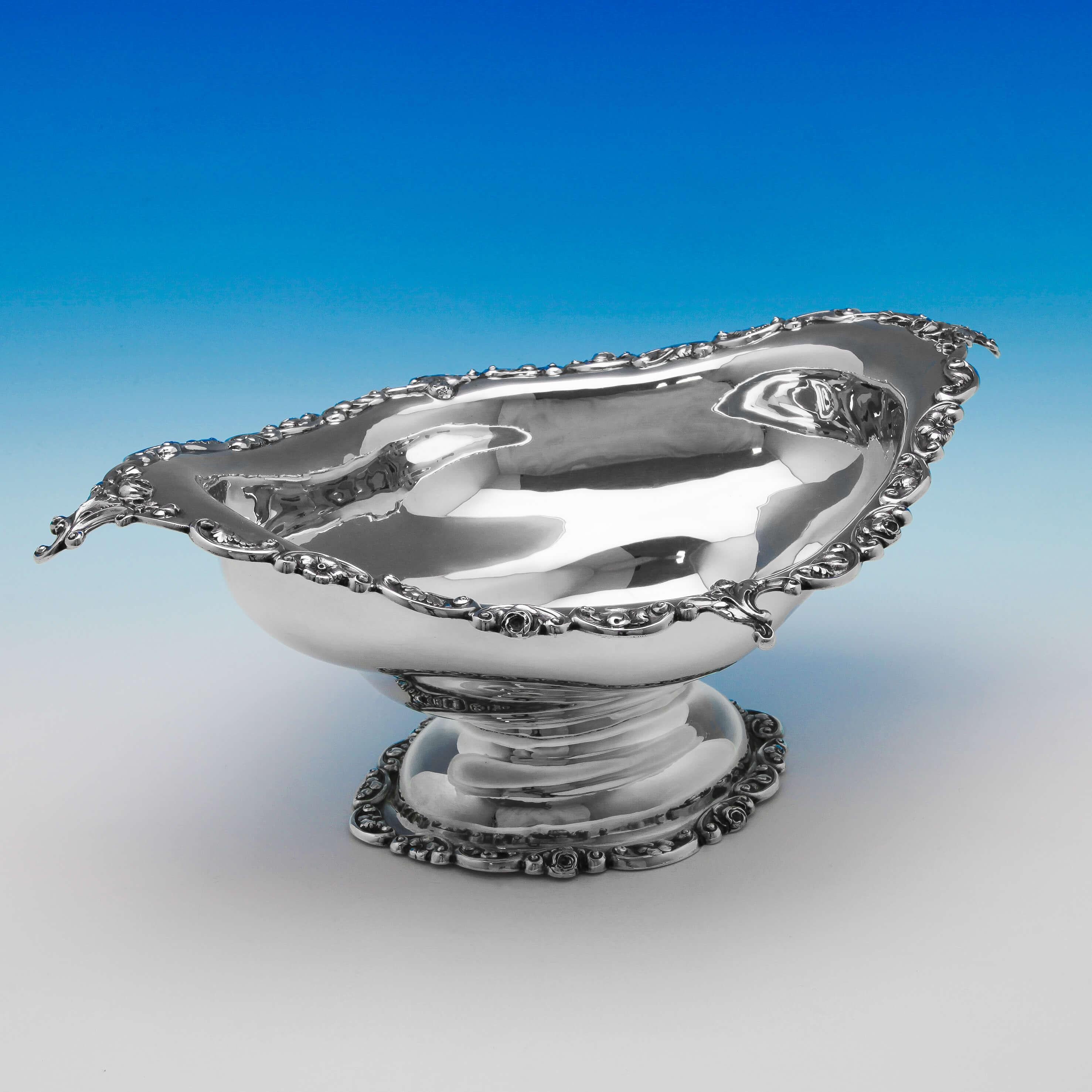 Hallmarked in Sheffield, 1909 by C. C. Pilling, this striking, antique sterling silver bowl, stands on a pedestal foot, and features ornate shell, acanthus and scroll decorated borders. The bowl measures: 6.25 inches (16cm) tall, by 16 inches