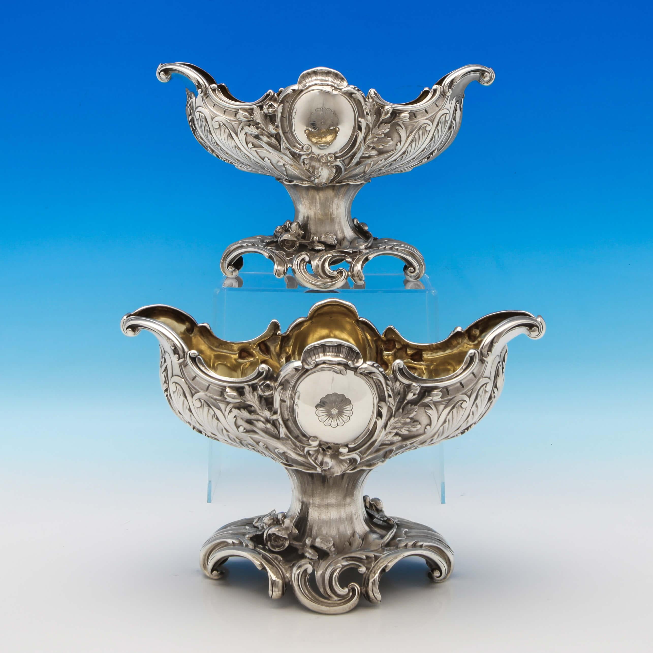 Hallmarked in Birmingham in 1898/9 by Elkington & Co., this fantastic quality, pair of Victorian, antique, sterling silver bowls, are oval in shape, featuring ornate chased decoration to the bodies and feet, gilt interiors, and an engraved crest to