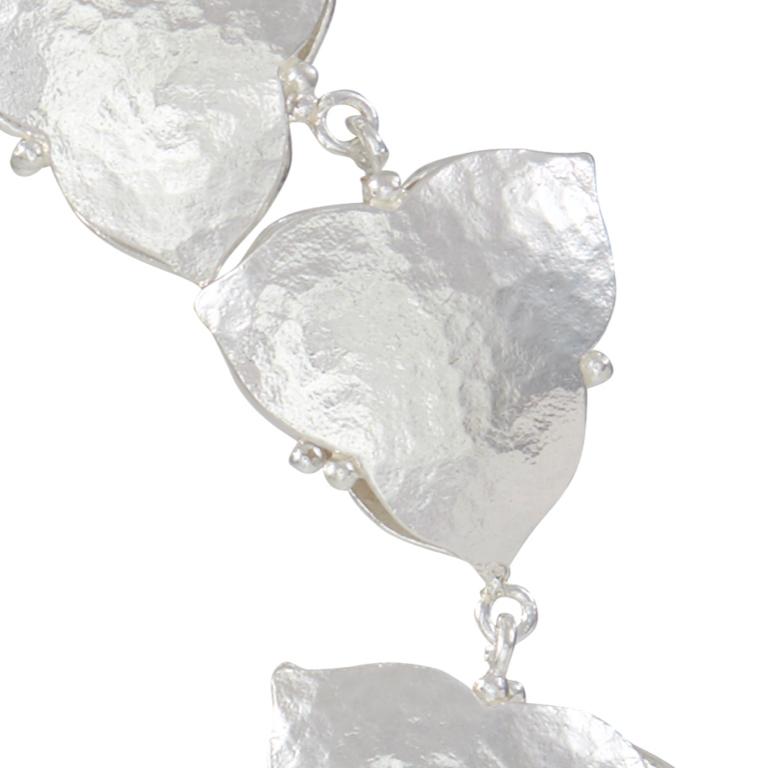 Cet élégant bracelet en argent sterling à finition martelée avec des pétales à double face est une pièce merveilleuse pour toutes les occasions.  Veuillez noter que cet article est fabriqué sur commande et qu'une pièce similaire mais non identique