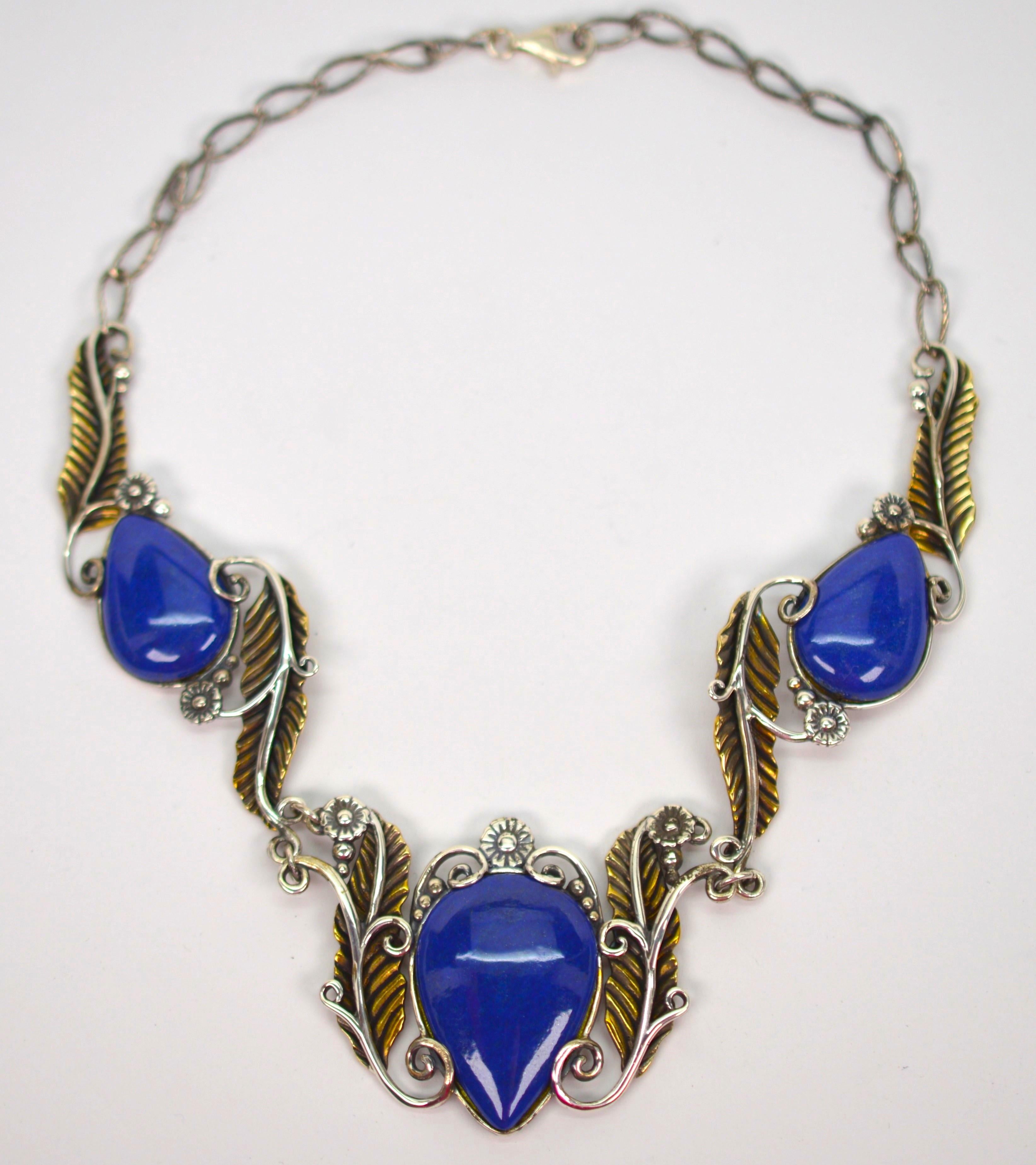 Deep blue pear-shaped Lapis cabochons bezel set in sterling silver display great color among the artful silver swirls and complimenting golden-toned brass leaves creating this Southwest inspired fashion necklace. From the American West Collection by