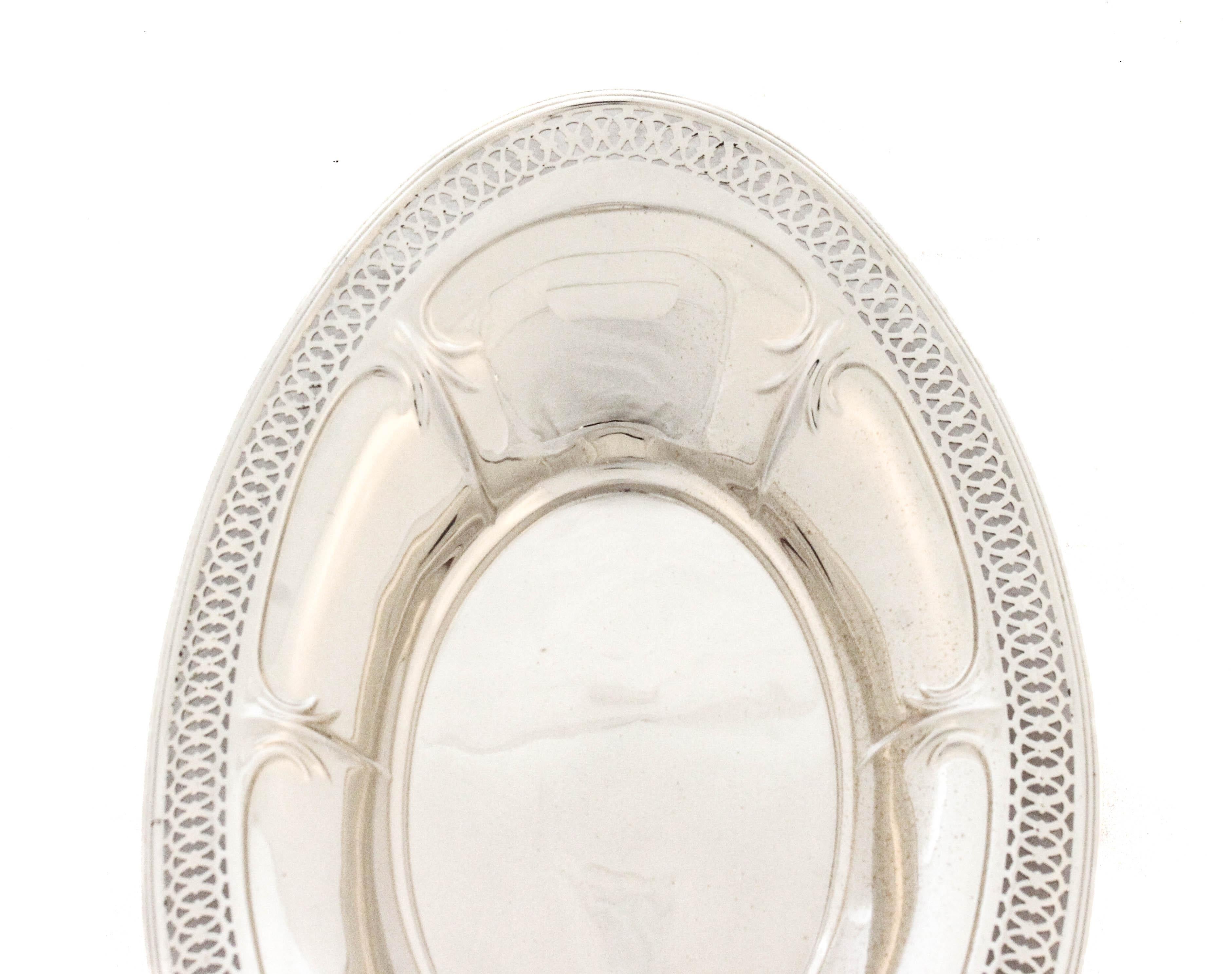Una panera de plata de ley fabricada por Meriden Britannia. Con unas medidas de 11 por 7 pulgadas, esta elegante cesta ovalada combina una refinada artesanía con un diseño atemporal. El borde presenta un delicado motivo reticulado -un diseño calado