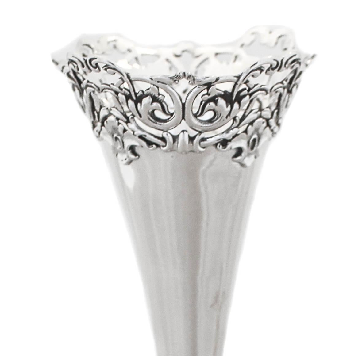 Being offered is a sterling silver bud vase by Theodore B Starr of New York, circa 1930’s. Both the top and base have an ornate open work design with scalloping that is rich and impressive. The vase opens outwards toward the top and has a trumpet