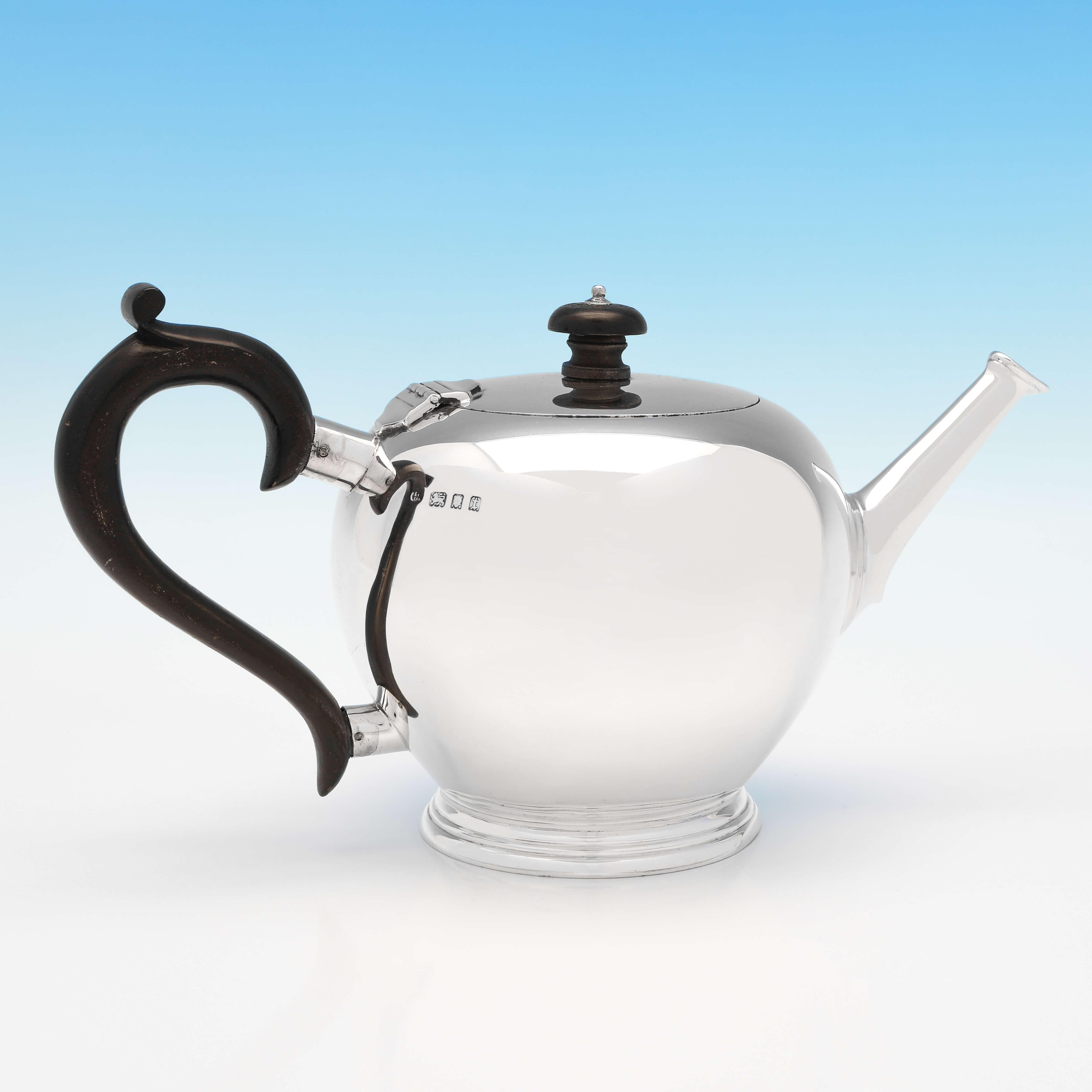 Hallmarked in London in 1934 by Blackmore & Fletcher Ltd., this handsome, Sterling Silver teapot, is in the 'Bullet' form, and has a wooden handle and finial. The teapot measures 6