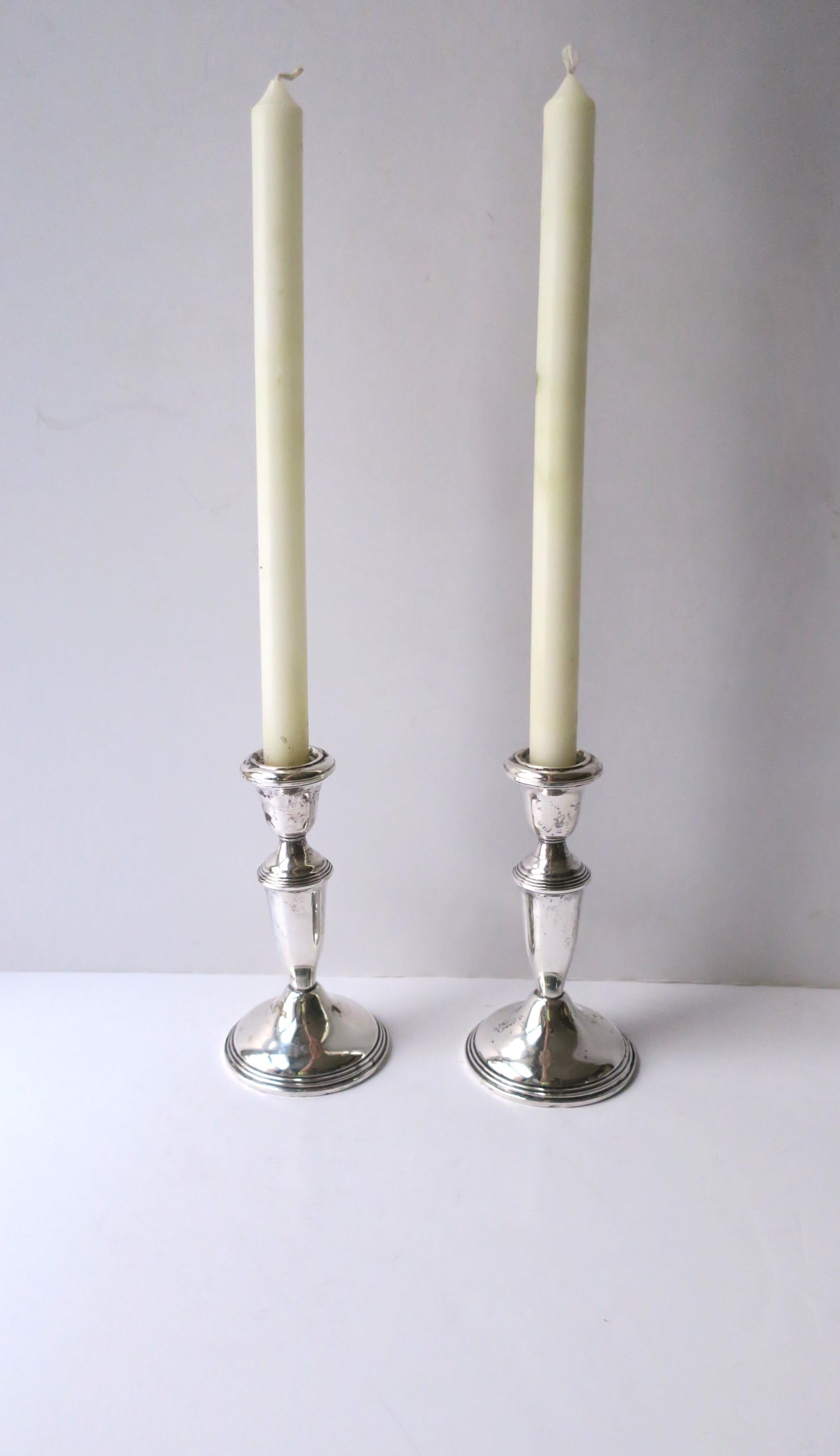 A pair (2) of sterling silver candlestick holders by Woodward & Lothrop, circa early-20th century, USA. A beautiful set with elegant details on candle cup, center, and circular edge base, all supported by a conical shaft. With marks' mark and