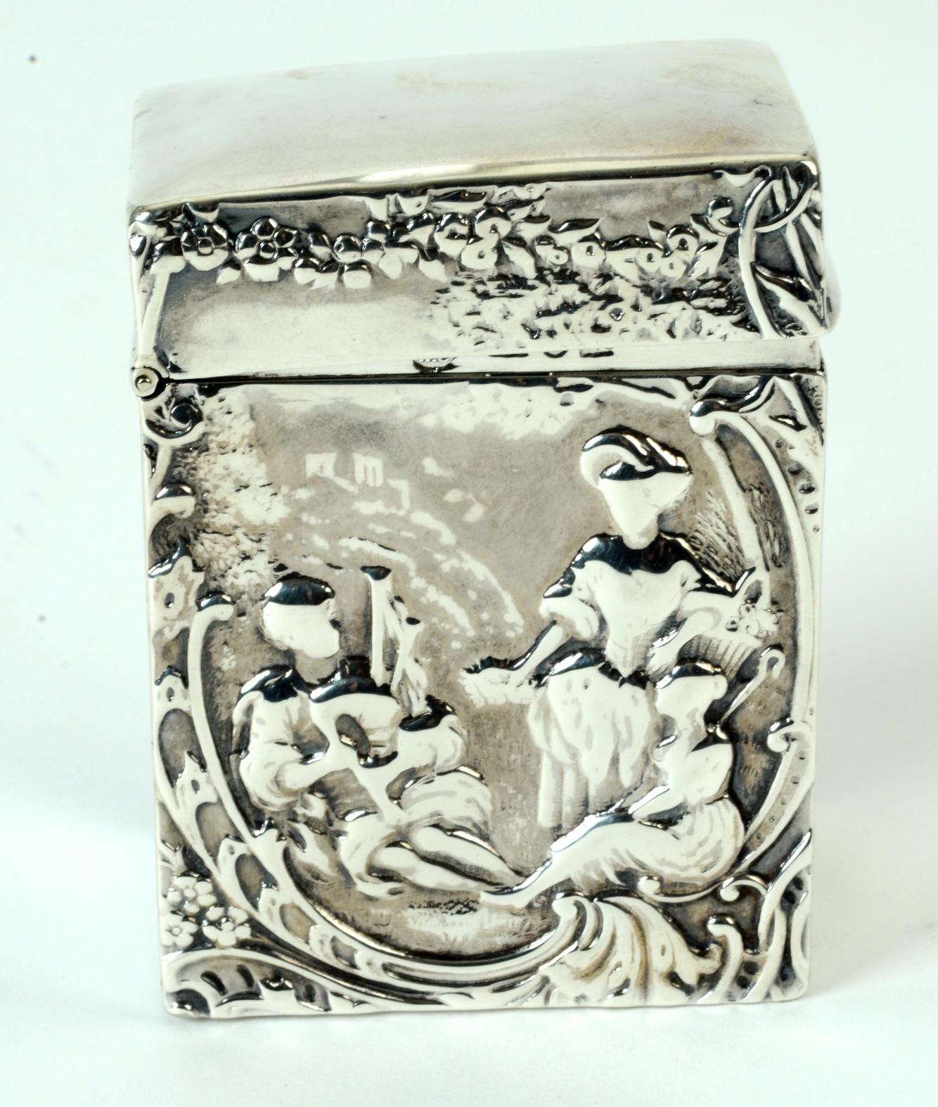 Sterling silver card case by Comyns of London, circa 1959. Comyns is one of the oldest and most prestigious English silversmiths. The case has a repoussé scene of people in a garden listening to music. Comyns was known for their repoussé work. The