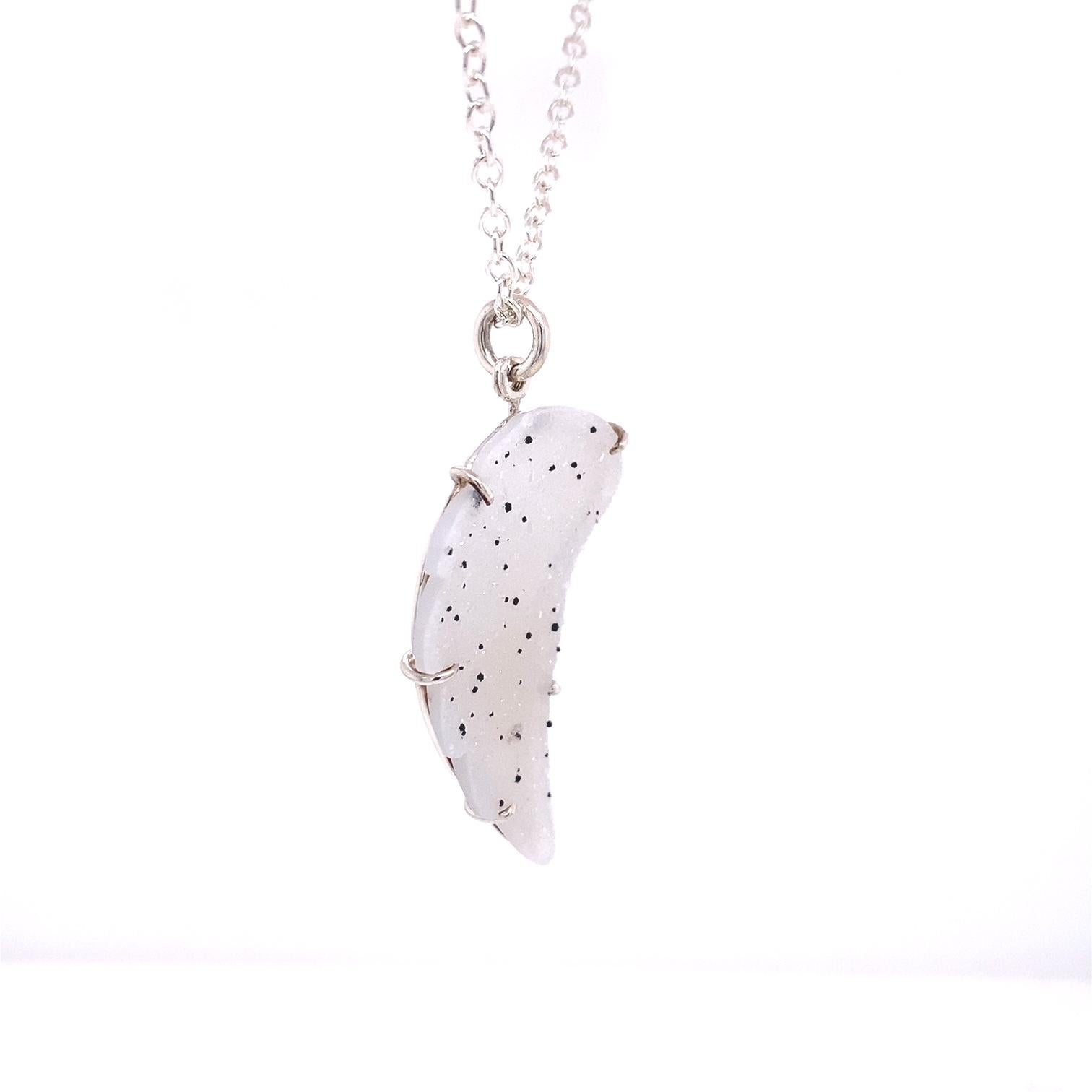 A sterling silver pendant prong-set with one carved translucent white speckled druzy wing on a 17