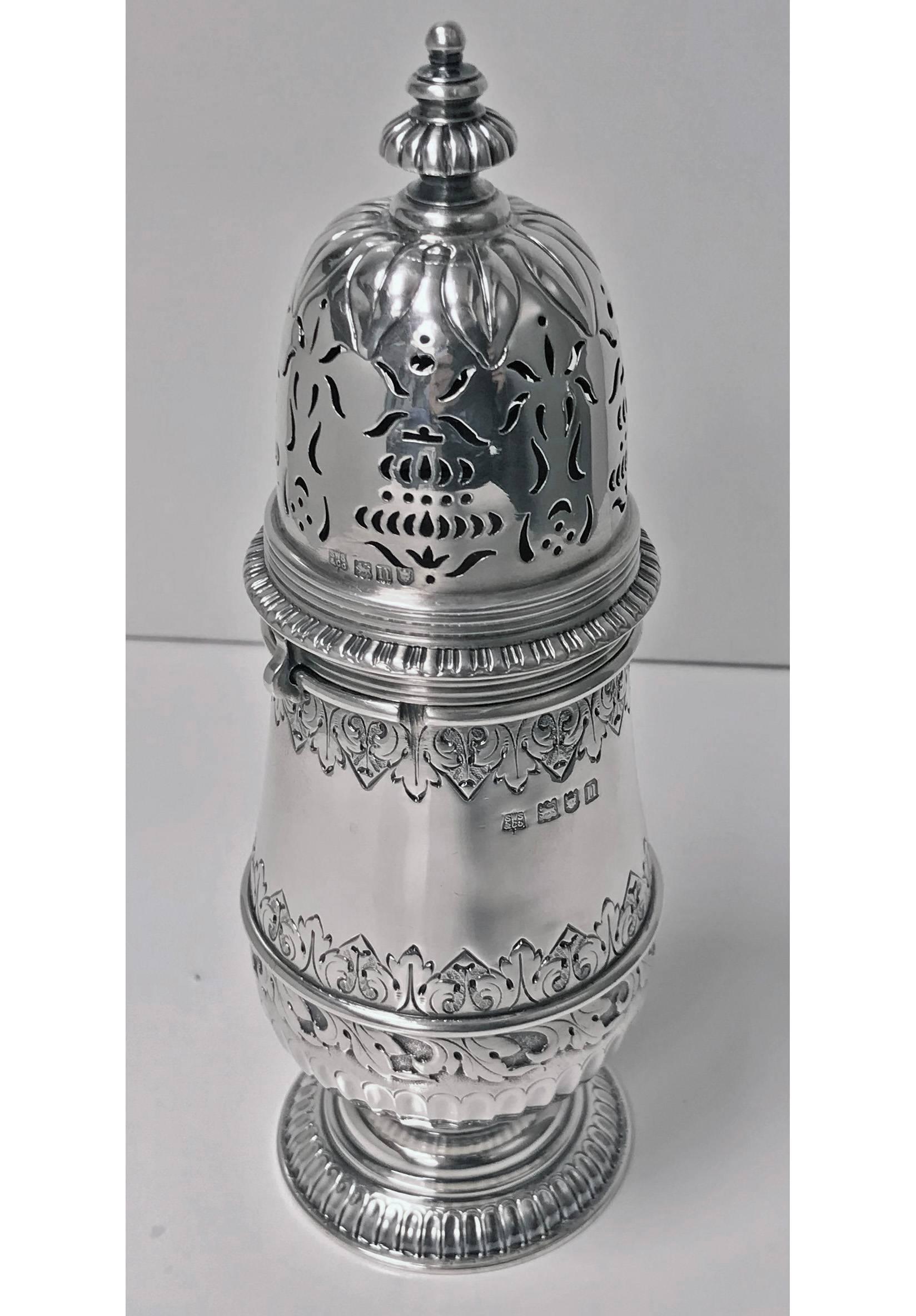 George II style Silver Caster, London 1912, S.W. Smith. Pear shaped, on spreading gadroon foot, the lower body and rim each applied with cut-card work, the bayonet mounted cover pierced with foliate scrolls populated by birds and with a stencil