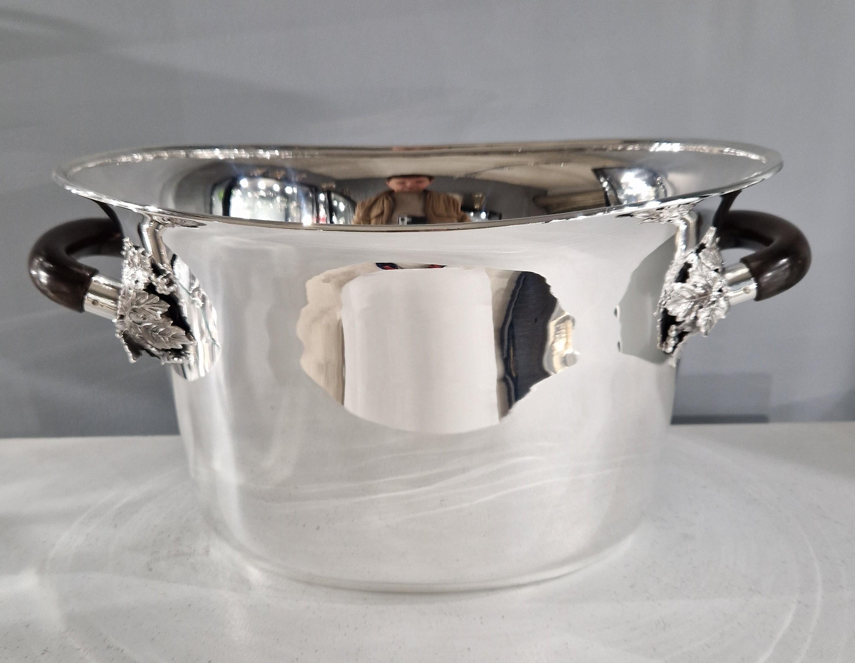 Un dispenser per champagne/vino in argento sterling di forma molto ovale. 
Ha un ampio bordo svasato e due maniglie laterali in legno con accenti decorativi in foglia d'argento.

Di Gabriel DeVecchi
1507 grammi
Italia anni '70