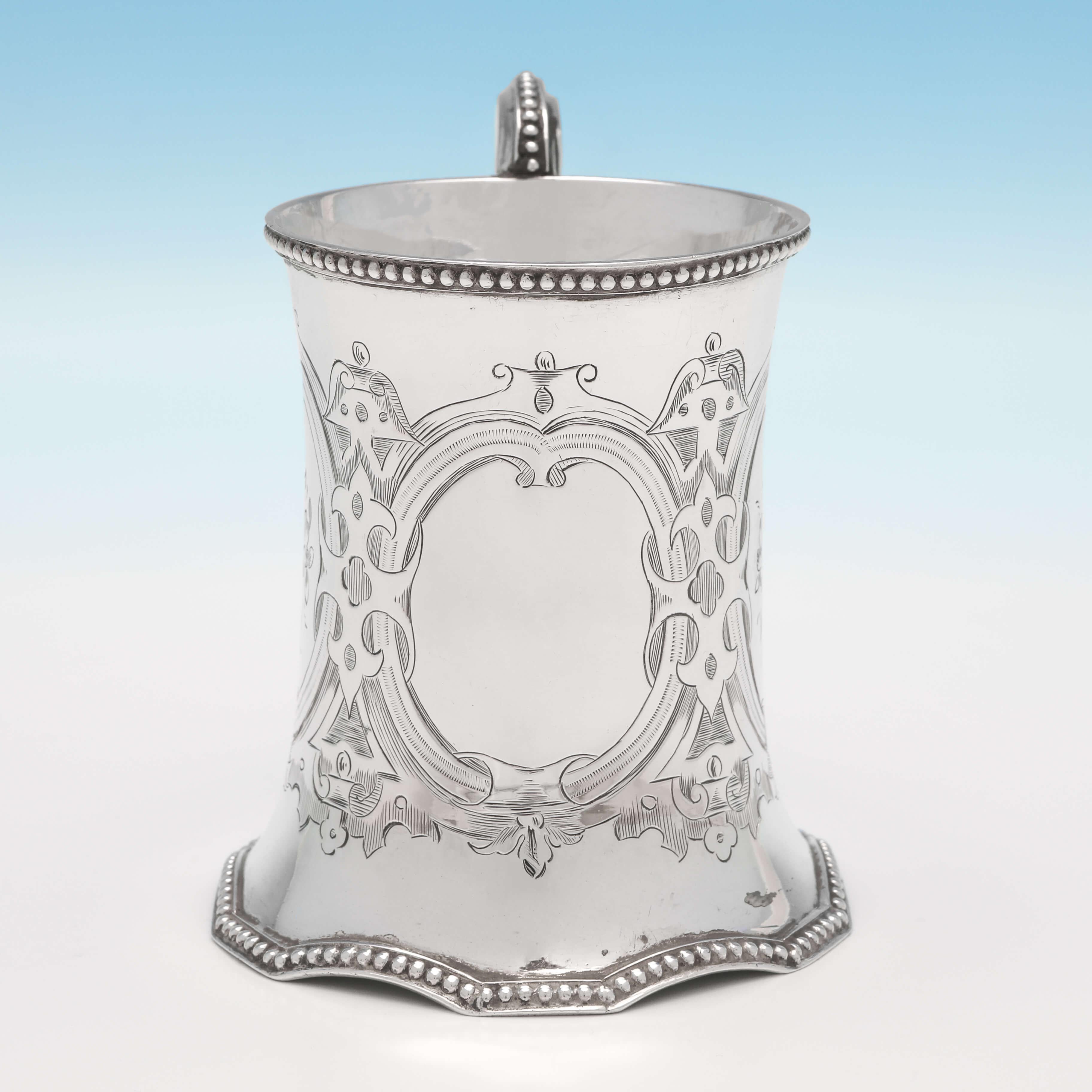 Hallmarked in London in 1858 by Robert Hennell II, this attractive, Victorian, antique sterling silver Christening mug, features bright cut engraved decoration throughout, bead borders and an unusual shaped base. The christening mug measures: 4