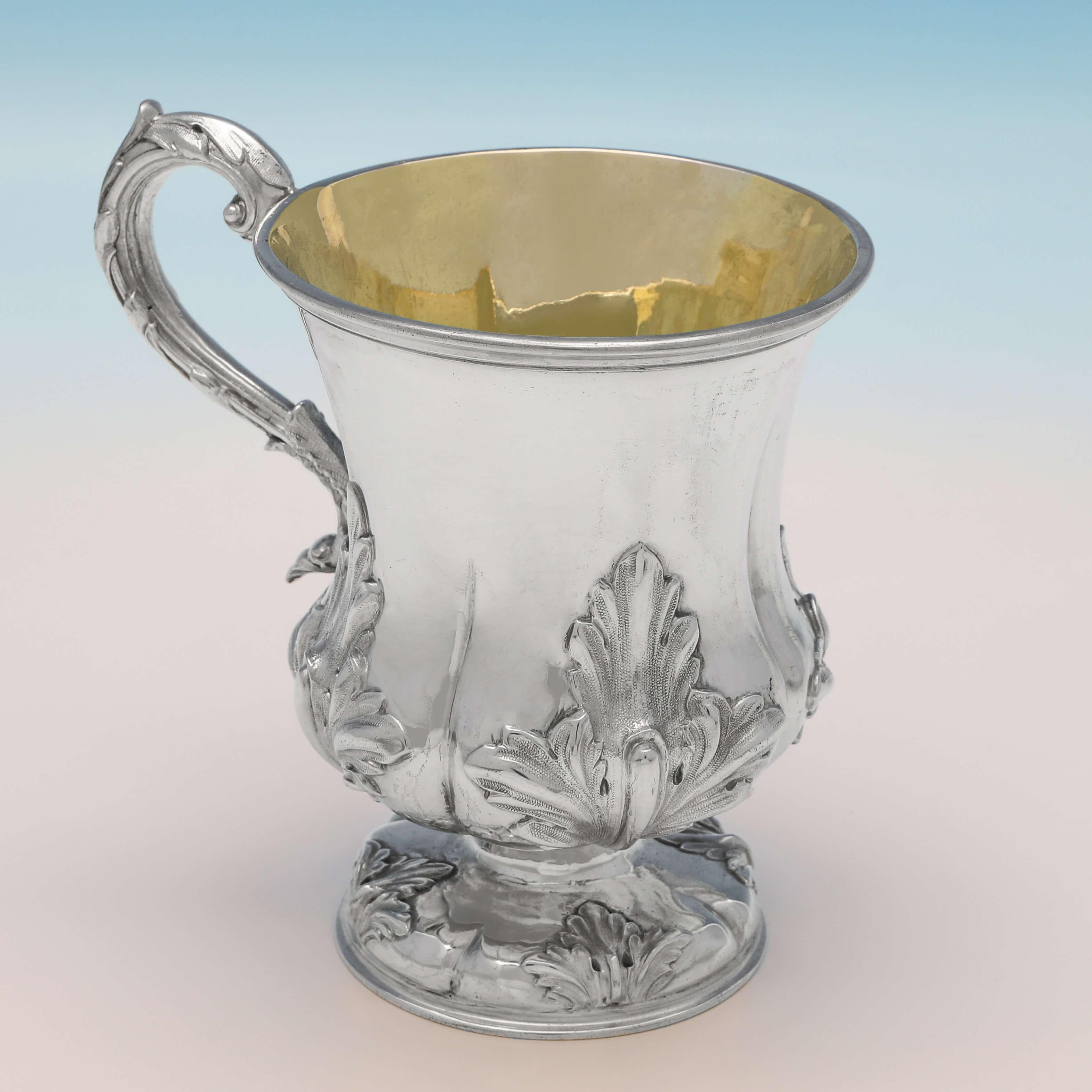 Hallmarked in London in 1840 by John Tapley, this stylish, Victorian, antique sterling silver christening mug, features chased acanthus decoration, a gilt interior and an acanthus detailed scroll handle. The christening mug measures 4.5