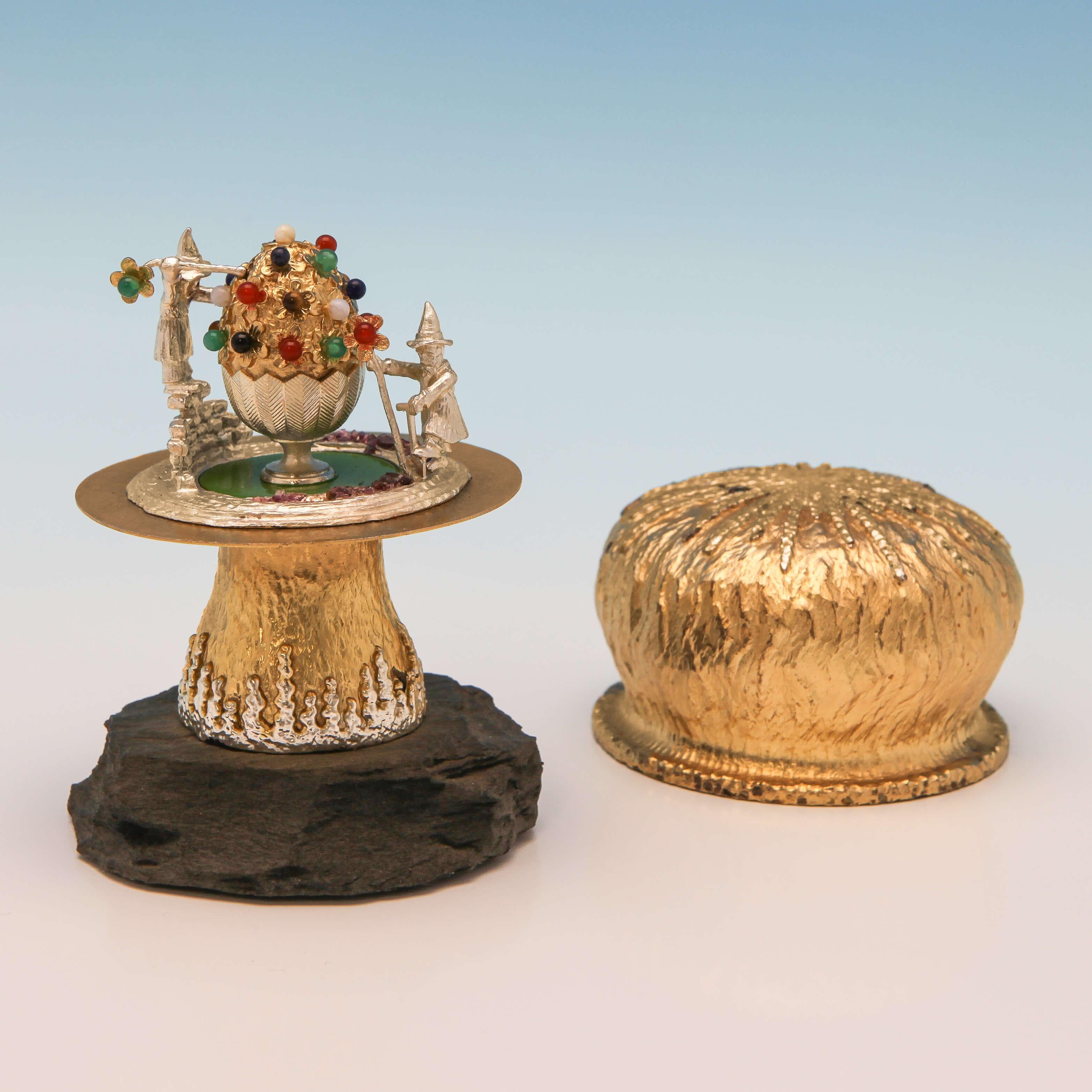 Hallmarked in London, 1982 by Christopher Lawrence, this fun and collectible sterling silver gilt novelty mushroom has a lift off cap, revealing two elves decorating an egg bejewelled in semi-precious stones. It stands on a slate base and measures
