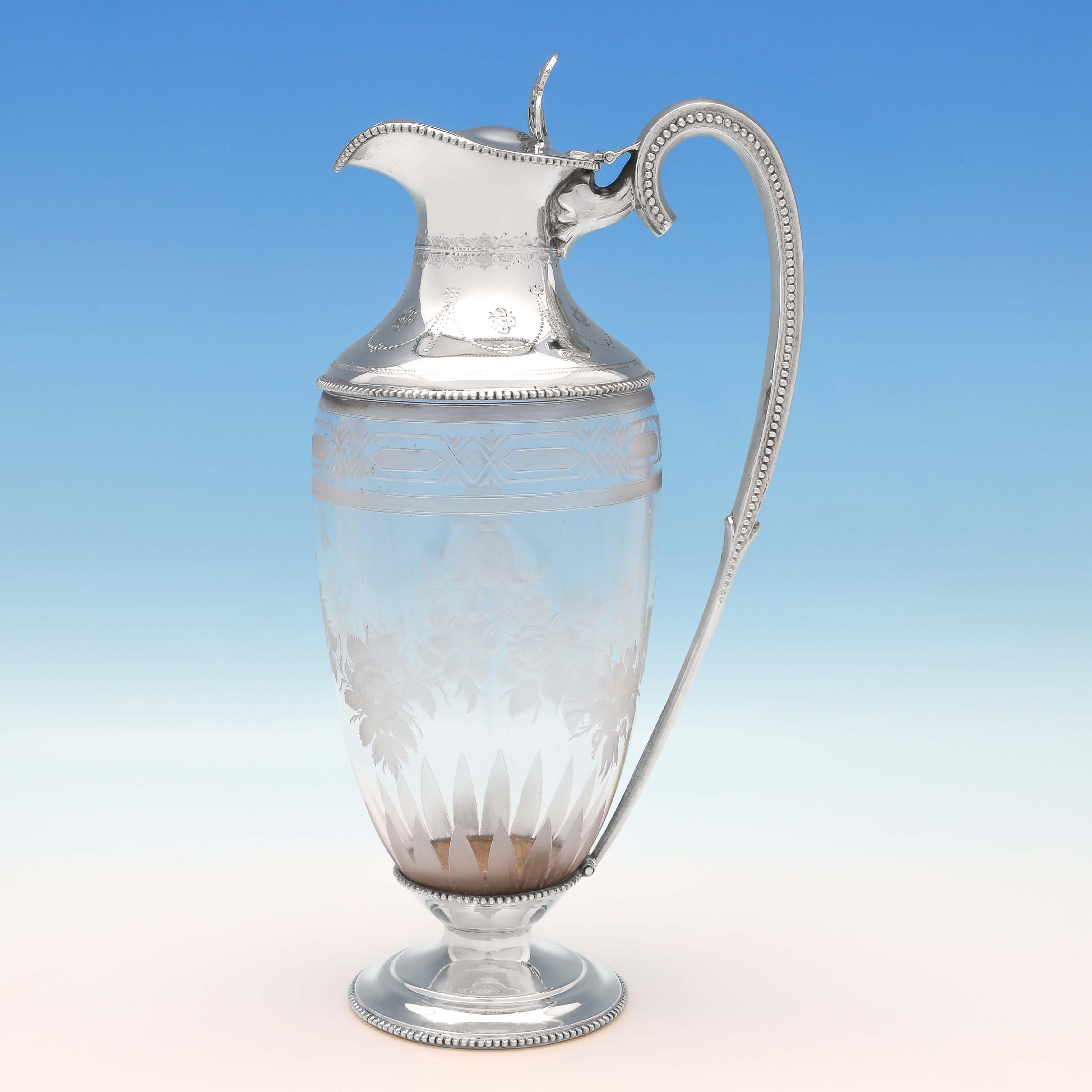 Hallmarked in London in 1868 by William & George Sissons, this attractive, Victorian, Antique Sterling Silver Claret Jug, is urn shaped, and features floral etched glass and a bright cut engraved mount, with bead borders. The claret jug measures