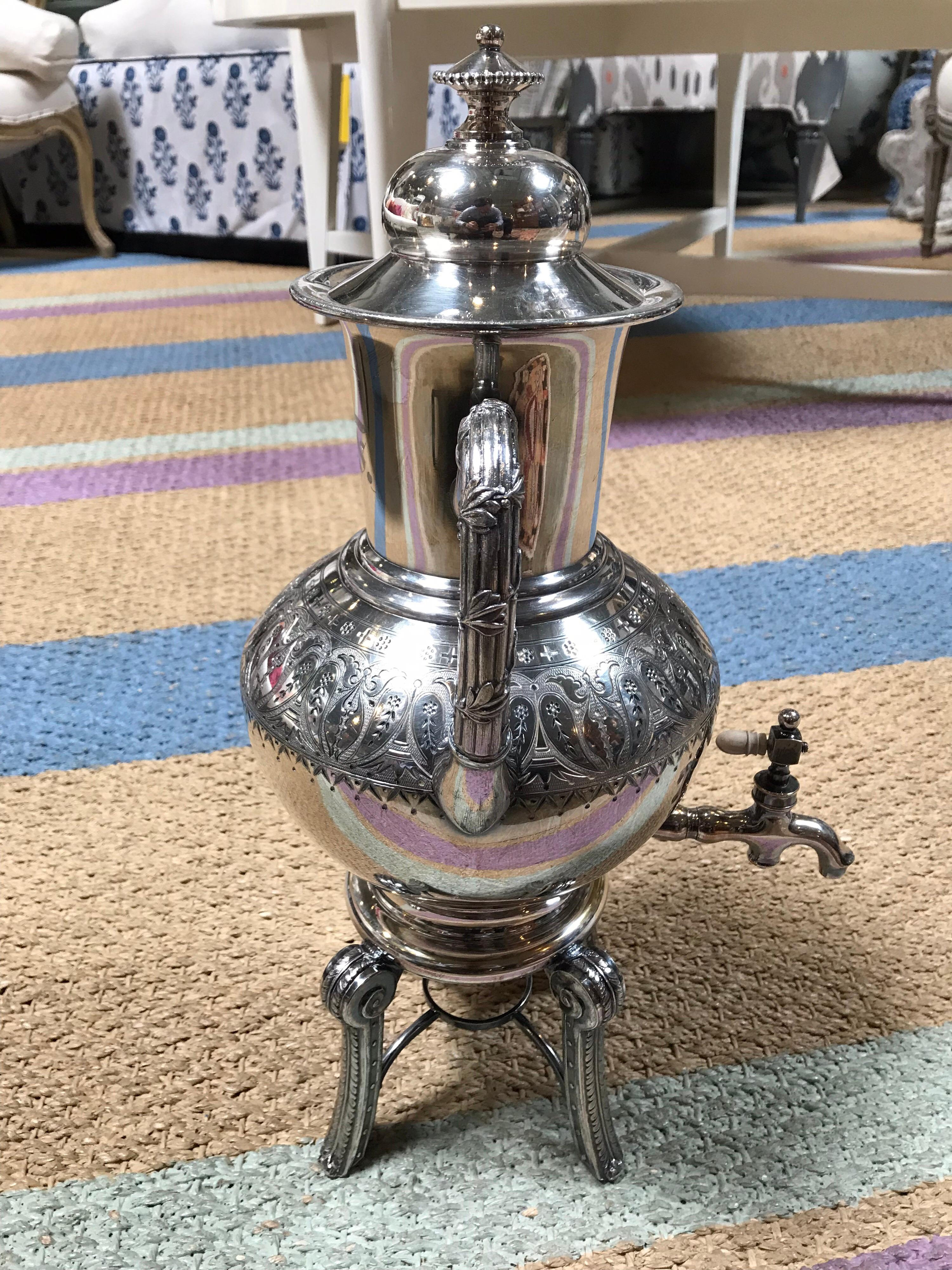 This ornately decorated coffee tea dispenser is made from sterling silver. It sits on four legs and has two side handles. The spout uses a traditional screw knob to control the flow of liquid. Quite the eye-catching center piece in the room.