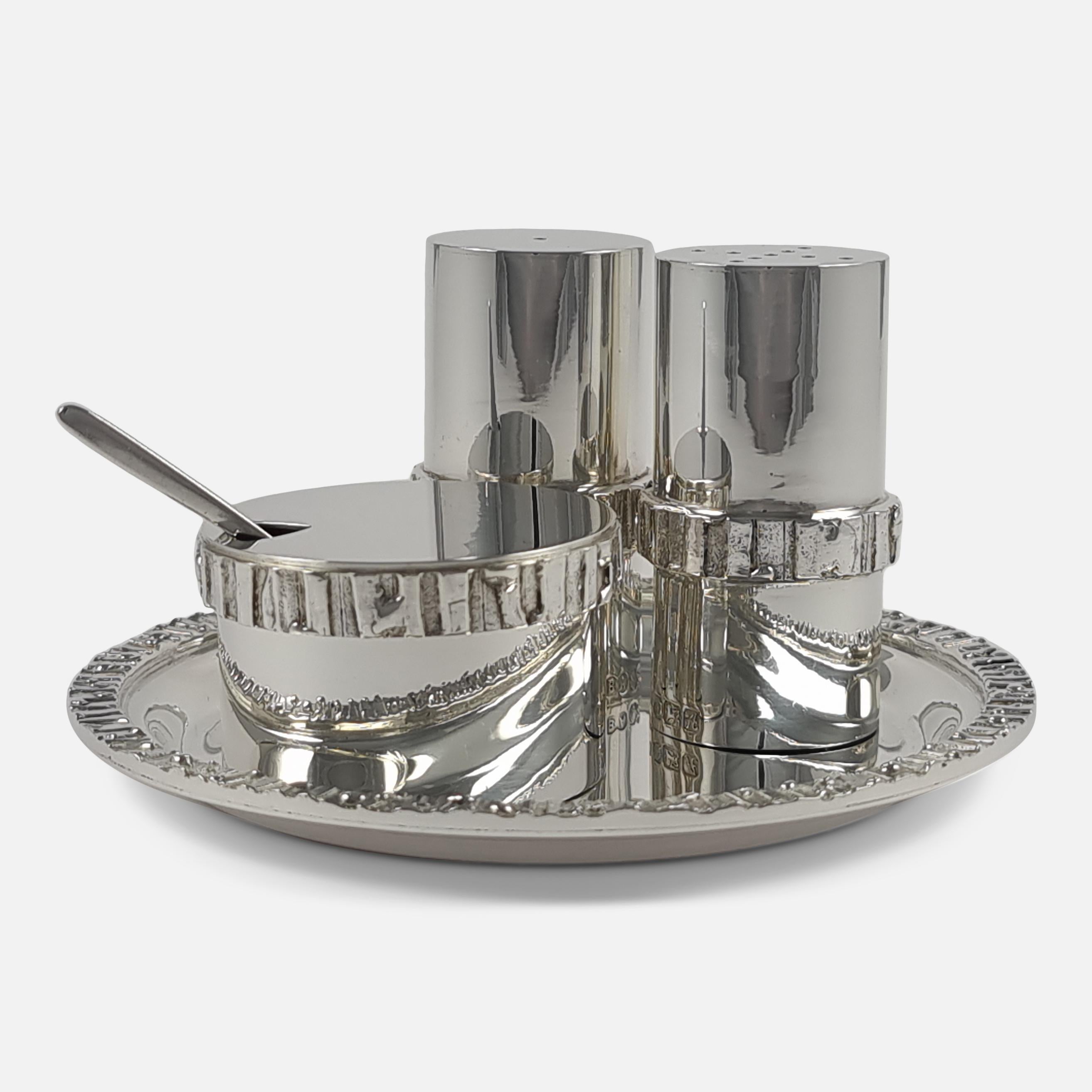 An Elizabeth II sterling silver three-piece condiment set and tray, by Brian Asquith, Sheffield, 1975. The condiment set consisting of a salt and pepper shaker, mustard pot, and tray are of round form, with textured banding. The associated mustard
