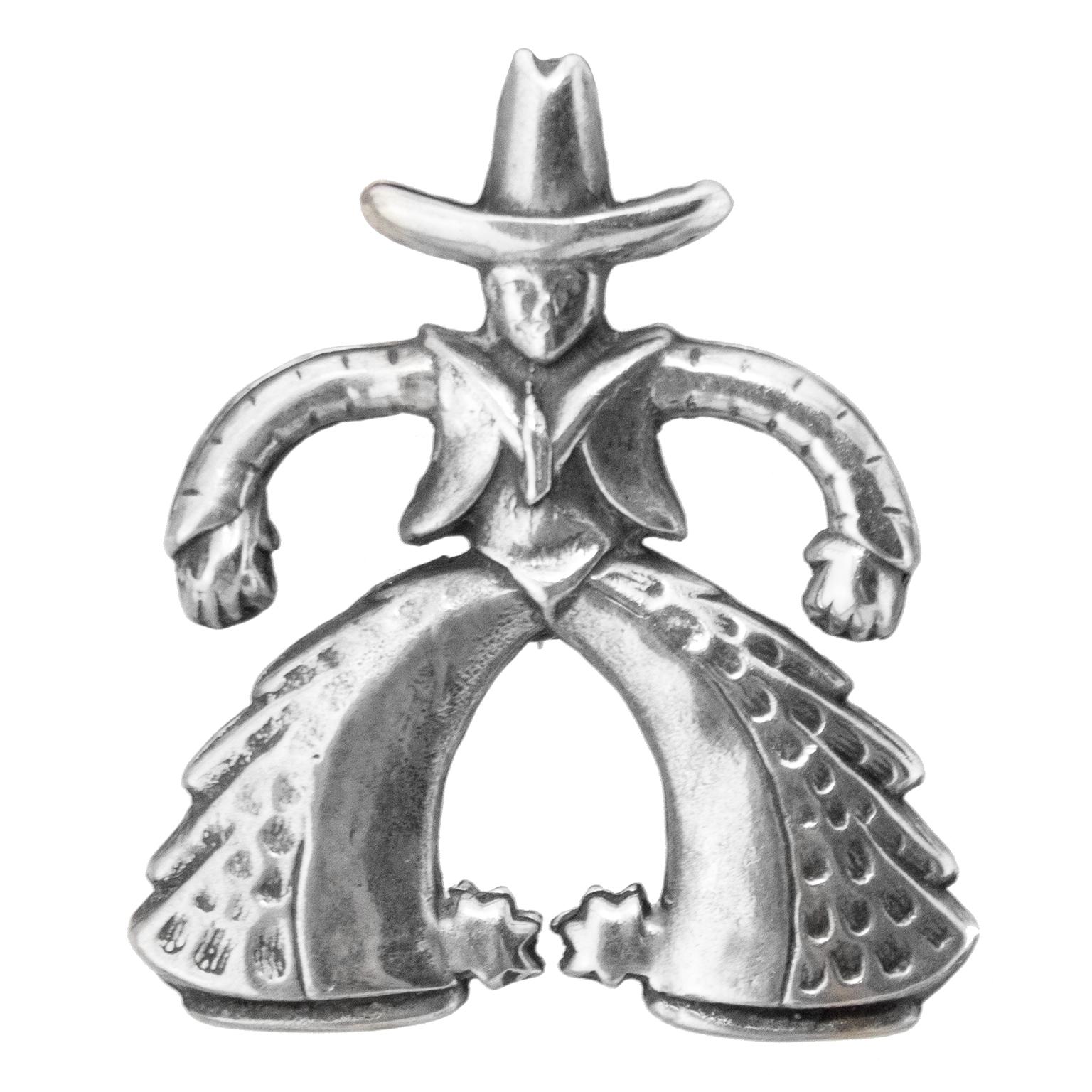 Fun 1950's sterling silver pin in the shape of a cowboy featuring an oversized hat, rounded arms, large rounded legs with fringe chaps and spurs on the back of his boots. Pin back sits vertically straight. Serling hallmark on back. Excellent vintage
