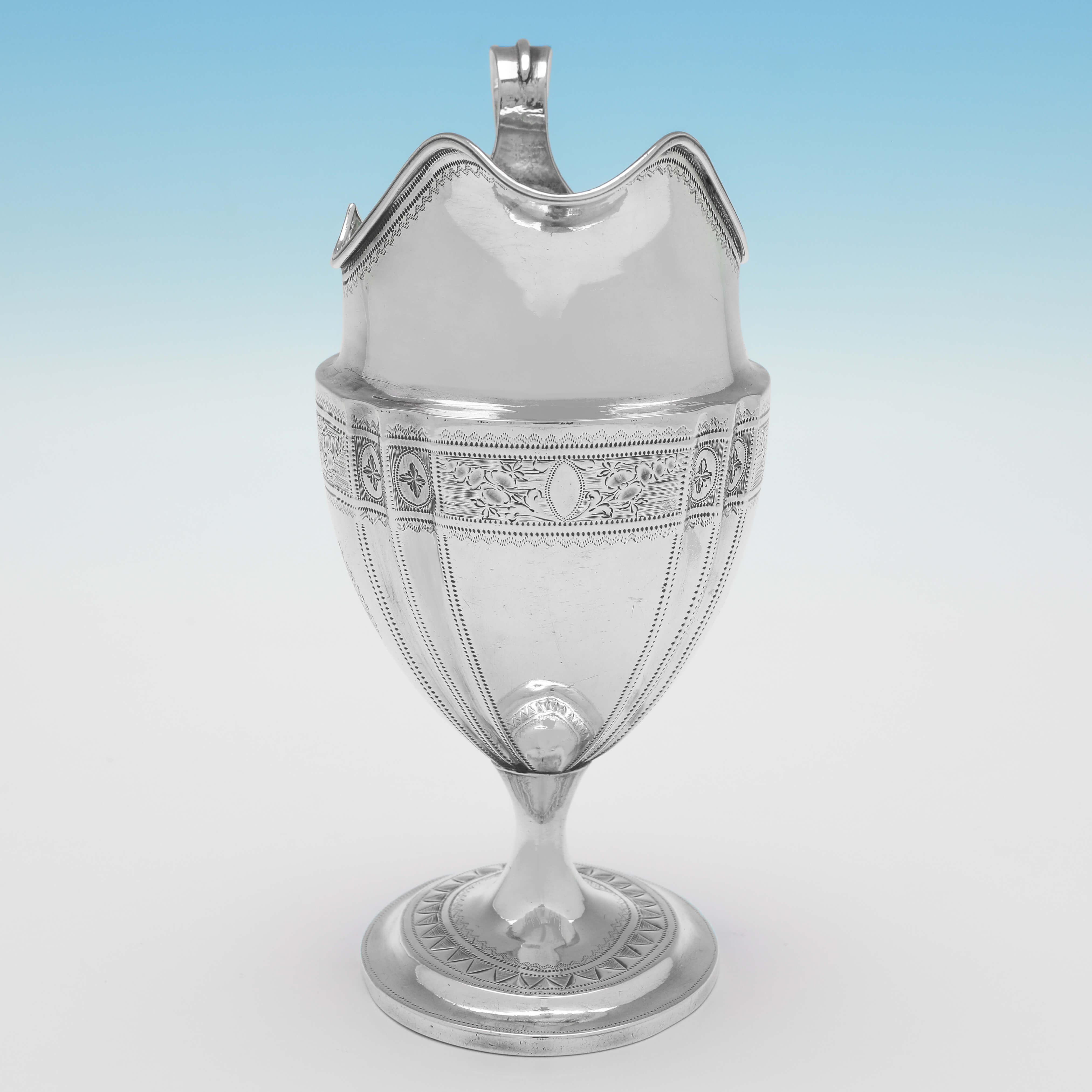 Hallmarked in Dublin in 1795 by Thomas Jones, this very attractive, Antique Sterling Silver Cream Jug, features wonderful brightcut engraved decoration to the body and foot, an engraved crest and a reed border around the rim. The cream jug measures