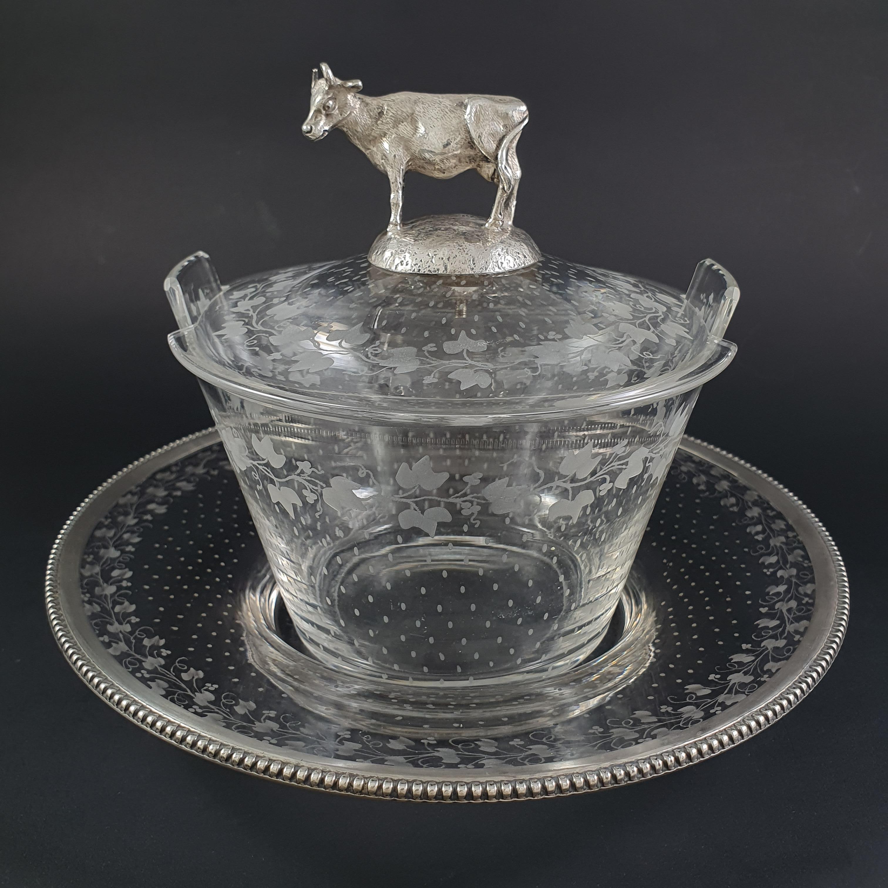 Butter dish in crystal and Sterlingilver from the 19th century 

The crystal finely engraved with leafy branches, the frame of the tray decorated with rows of pearls, the grip in the shape of a finely chiseled cow in the natural way 

Hallmarked