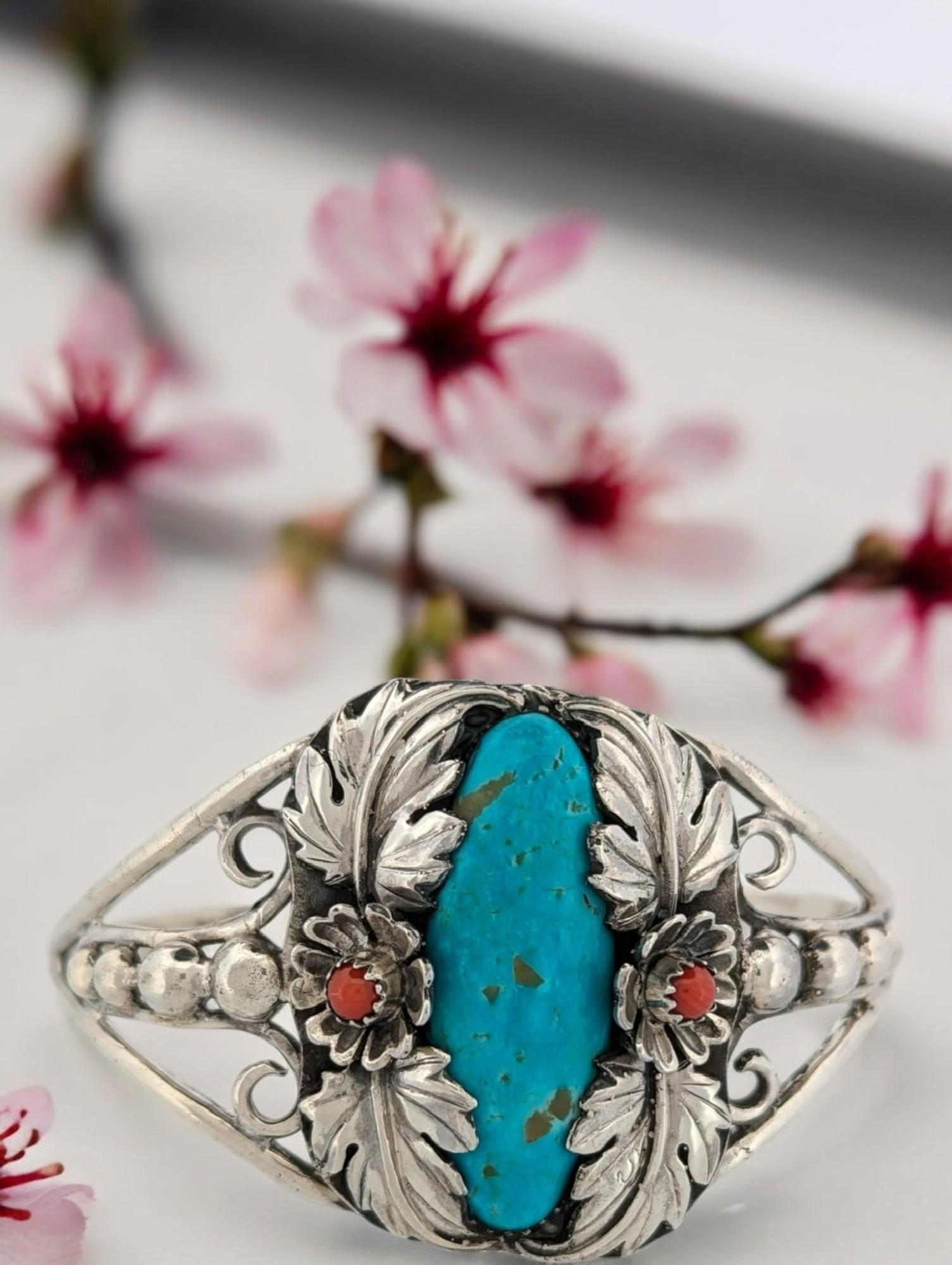 This captivating cuff bracelet is a testament to the artistry of Robert Drozd. Crafted from gleaming sterling silver, the bracelet features vibrant coral accents that add a touch of whimsy. The centerpiece, however, is the stunning Kingman turquoise
