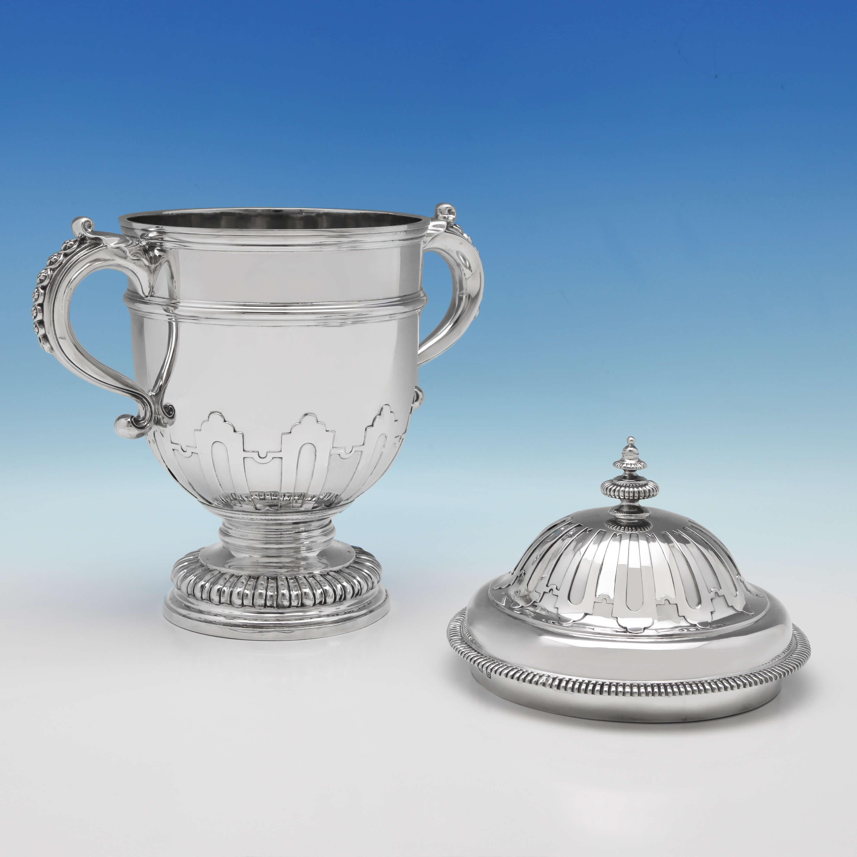 Hallmarked in London in 1937 by Richard Comyns, this handsome, sterling silver cup and cover features cut card decoration, gadroon borders, a fluted foot and acanthus leaf and floral decoration to the handles. The cup measures 13.5