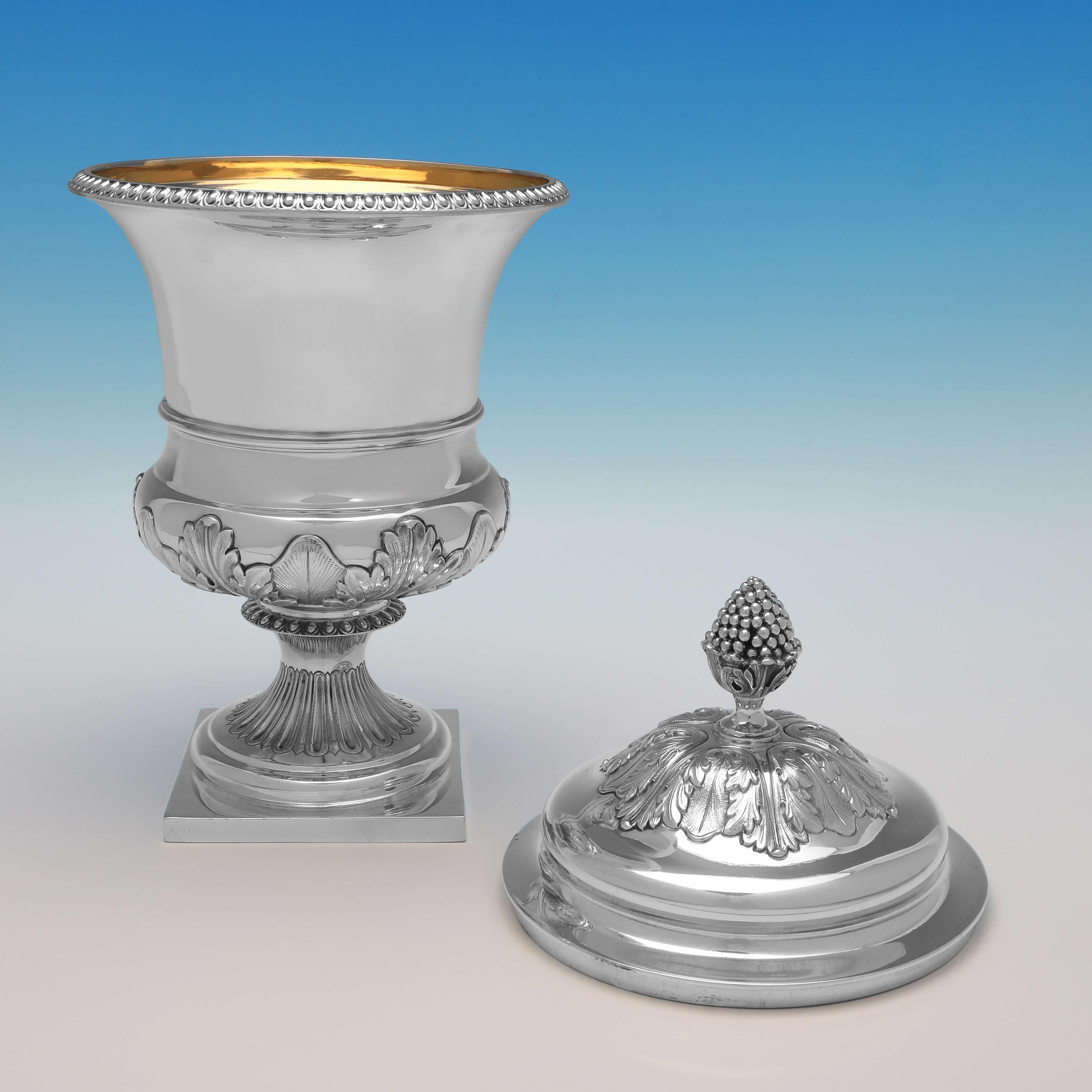 Hallmarked in London in 1928 by Reid & Sons, this Sterling Silver Cup & Cover, stands on a square base, and features a gadroon border and chased acanthus decoration to the body and lid. The cup & cover measures 13