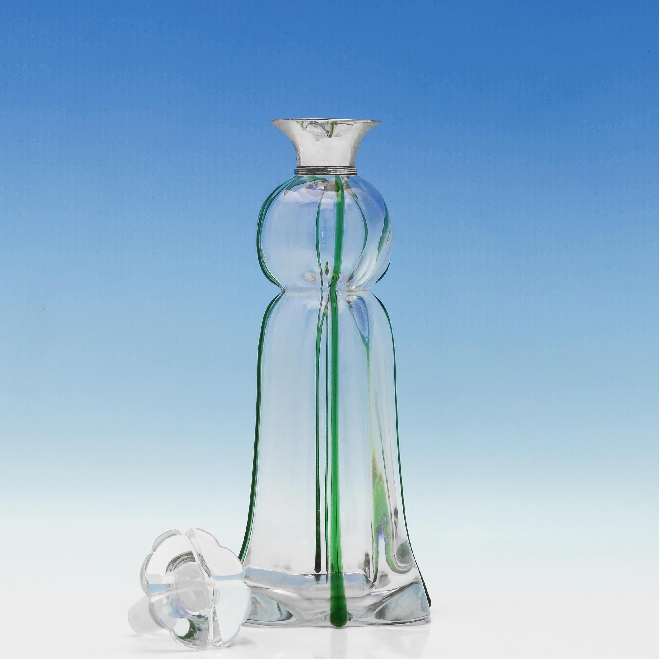 Hallmarked in London in 1900 by Heath & Middleton, this fabulous Art Nouveau, antique, sterling silver decanter features beautiful hand blown glass with green highlights, a plain reeded silver collar and a flower shaped stopper. The decanter is 12